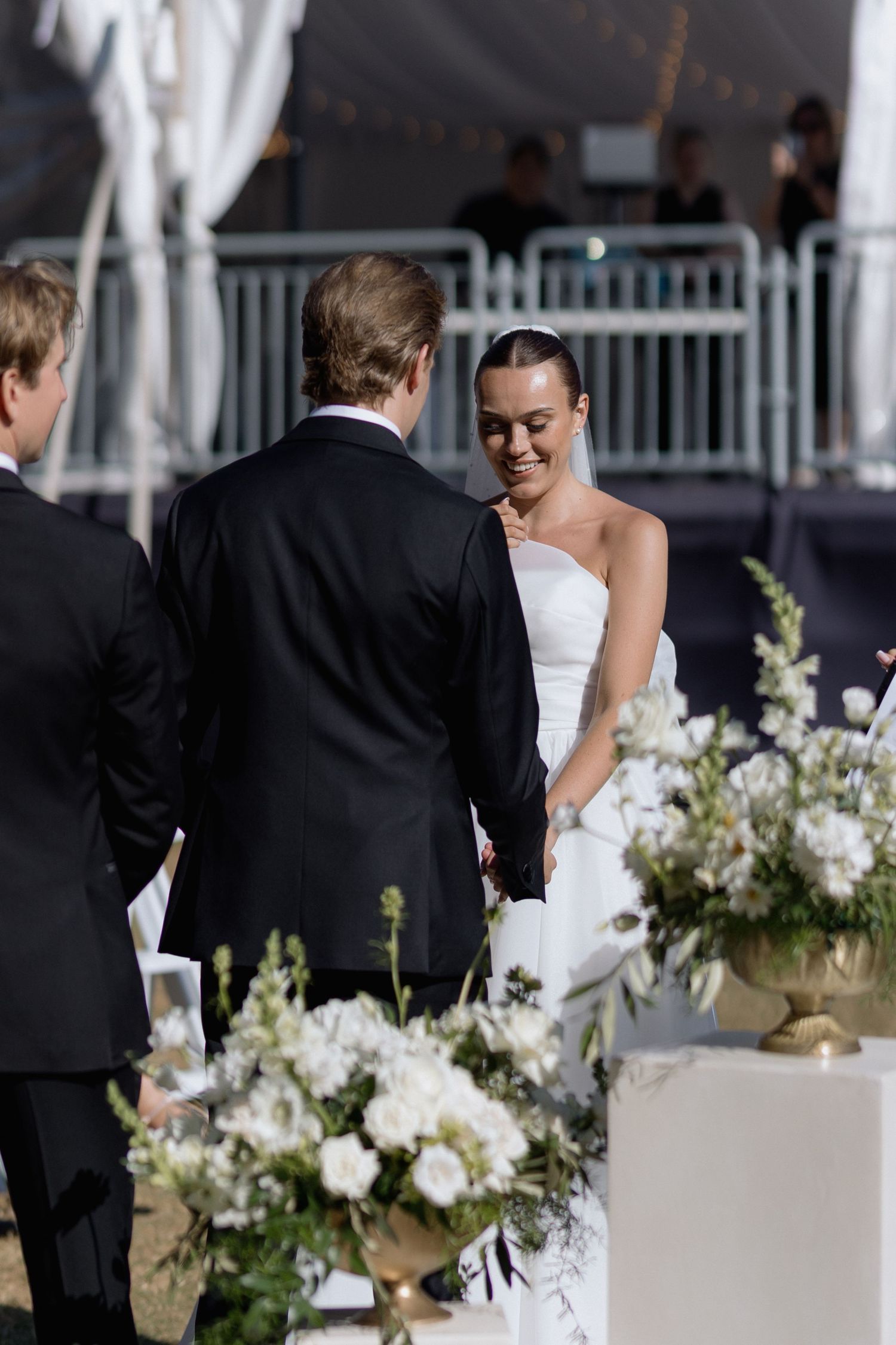 Elegant white floral arrangements and decor at an outdoor wedding ceremony.