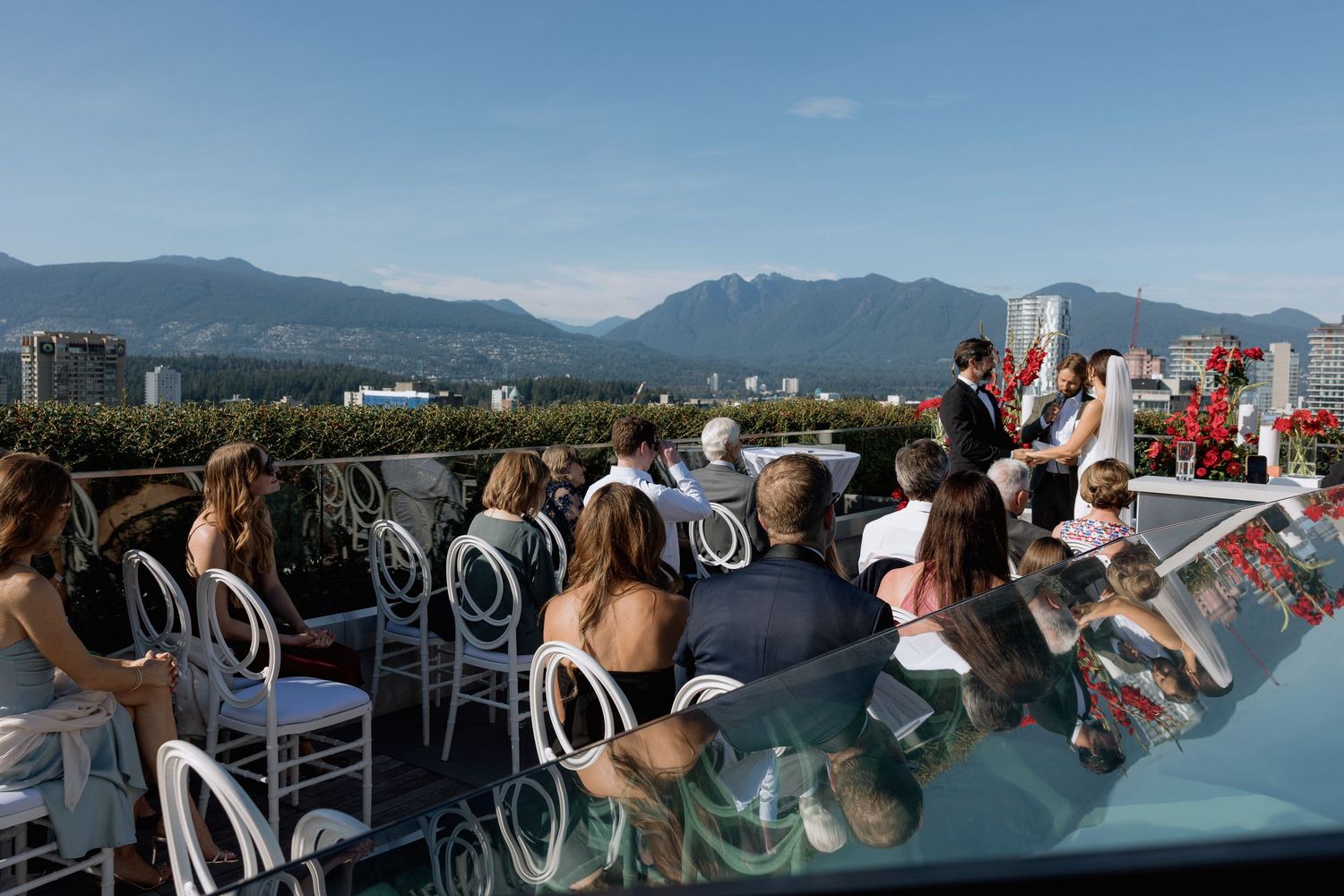 Panoramic view of Vancouver's skyline and mountains from a cruise ship deck with passengers enjoying the scenery.
