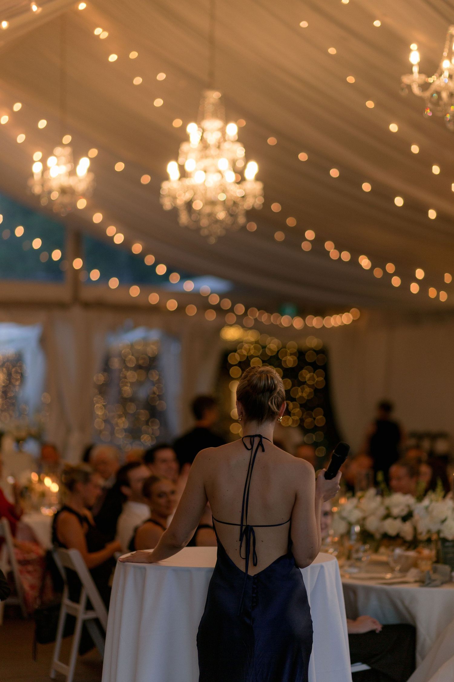 Elegant wedding reception venue with chandeliers and string lights creating warm ambiance.