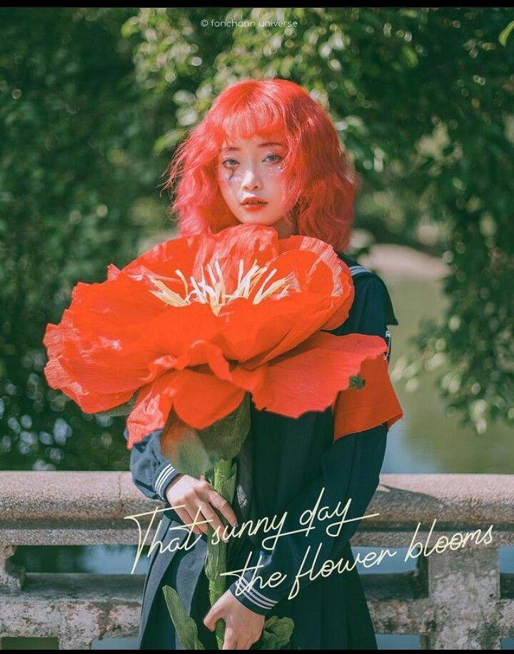 A red-haired girl holds a large red poppy flower with text reading That sunny day the flower blooms.