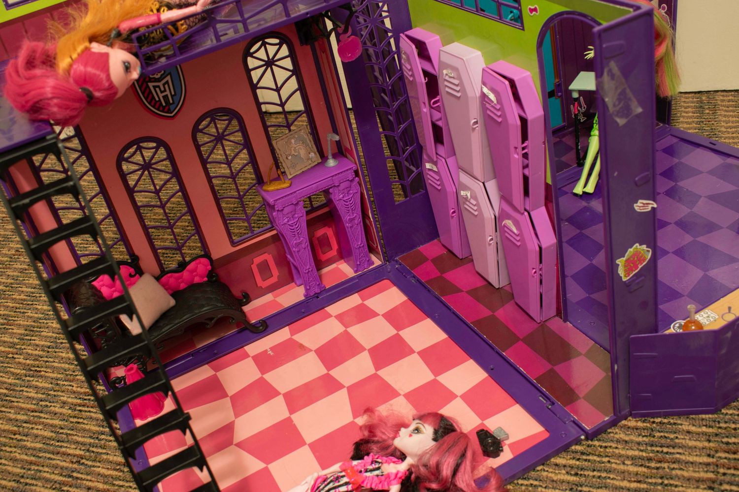 Monster High doll playset with pink checkerboard floor, purple lockers, and castle entrance displayed open on a table.
