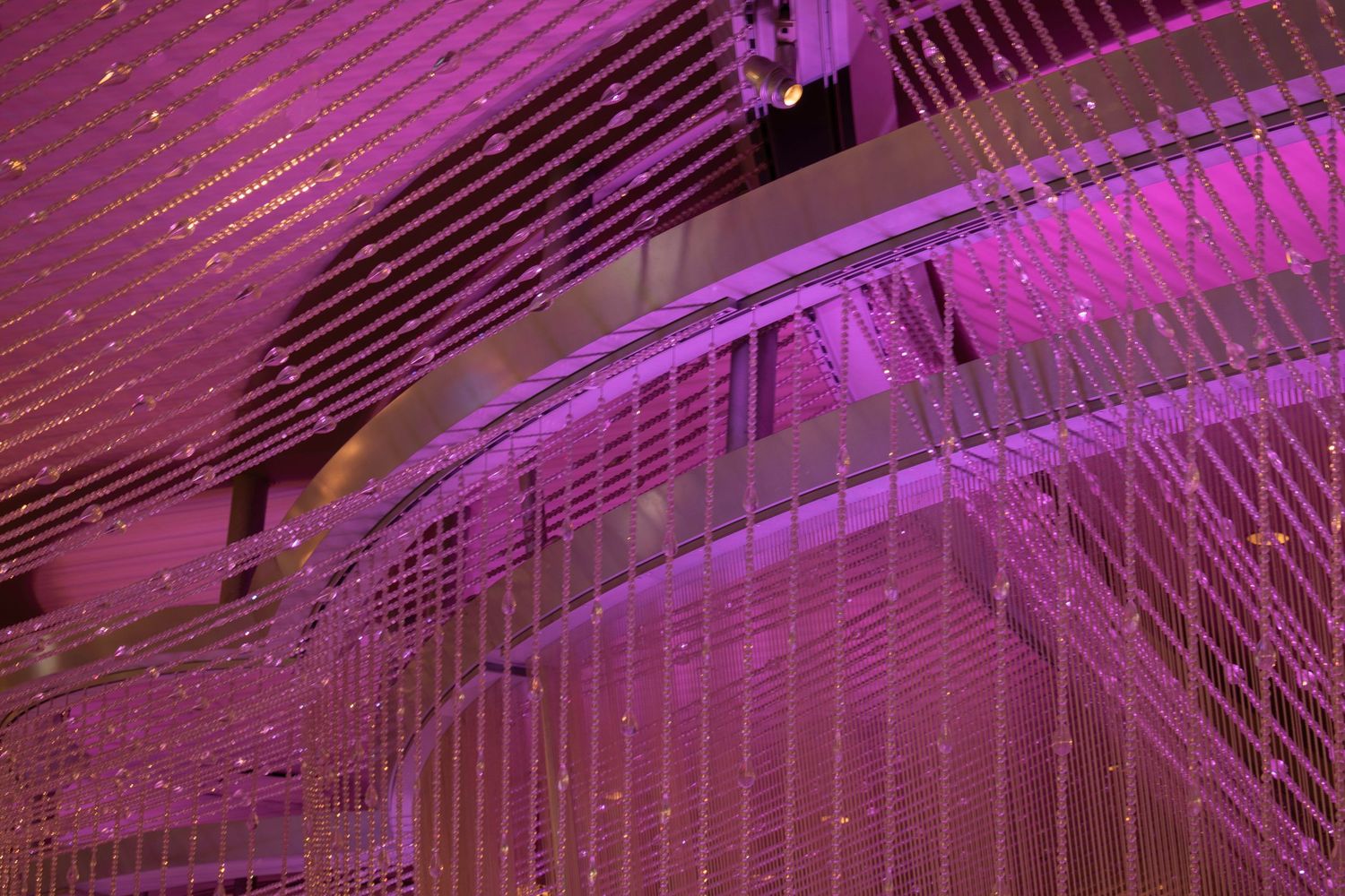 Abstract purple-lit interior with cascading crystal curtains and curved architectural elements.