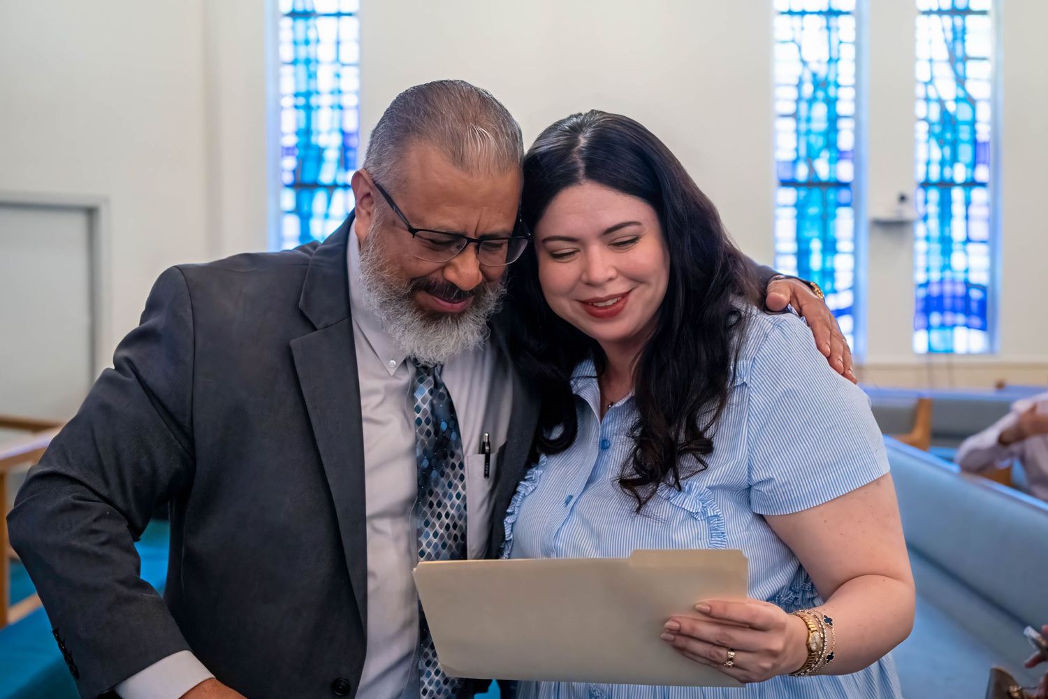 Priest and parent reviewing baptism documents together inside the church after the ceremony.