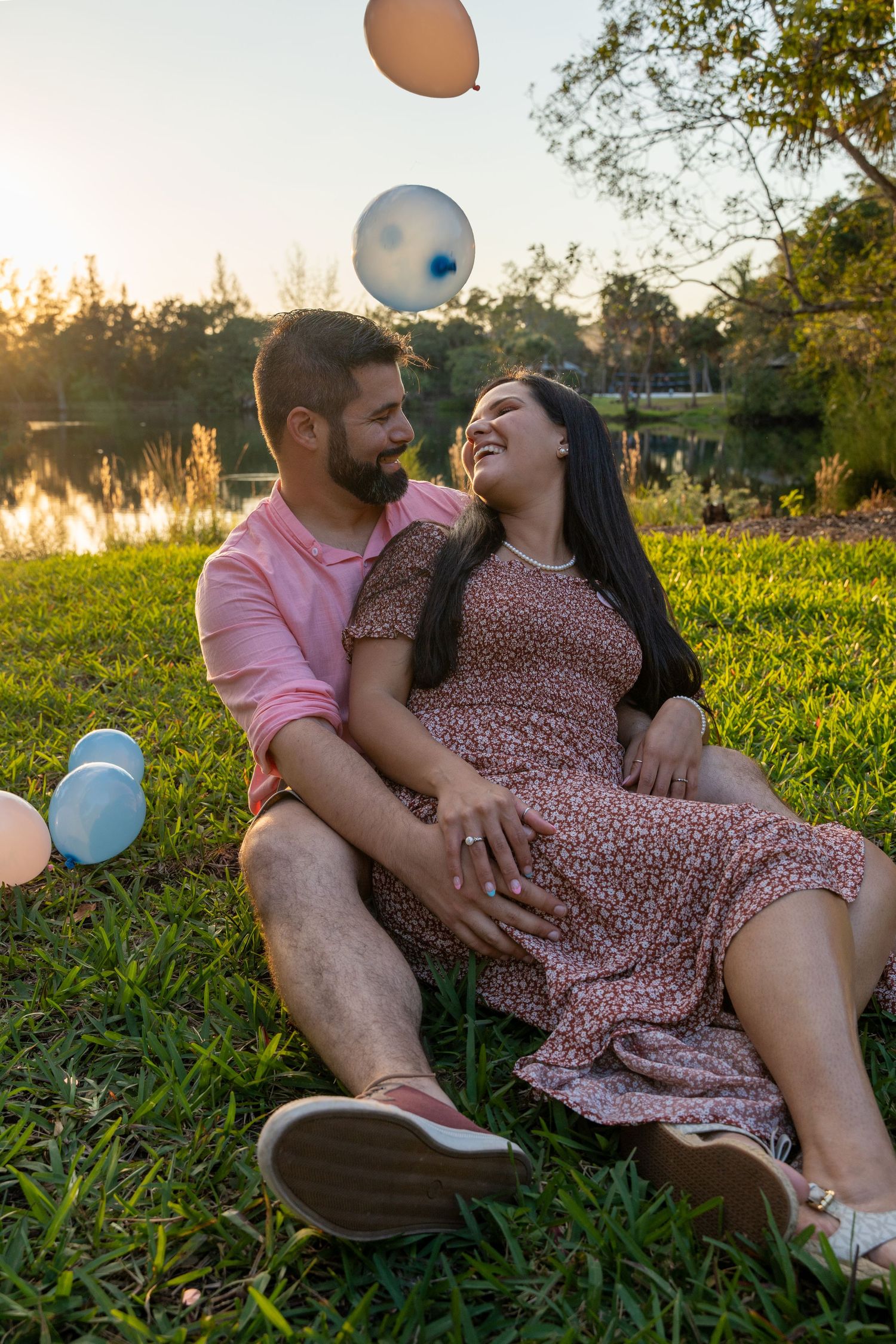 Maternity couple sitting together in a park, sharing a quiet moment surrounded by soft evening light.