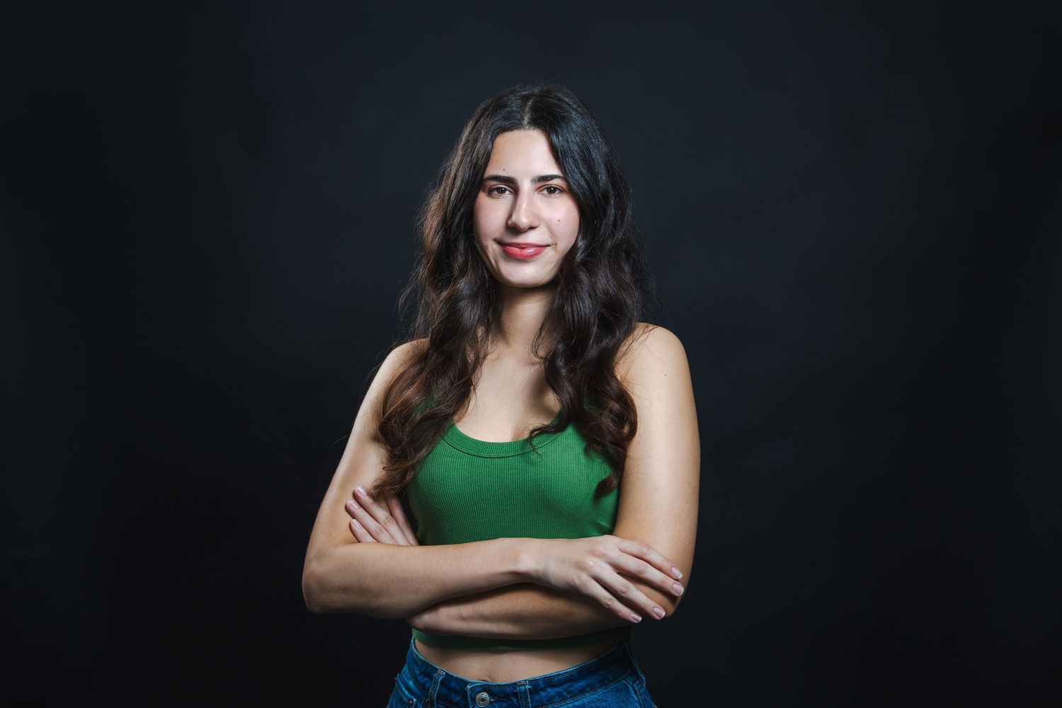Studio acting headshot of a woman with arms crossed, photographed against a dark background with soft professional lighting.