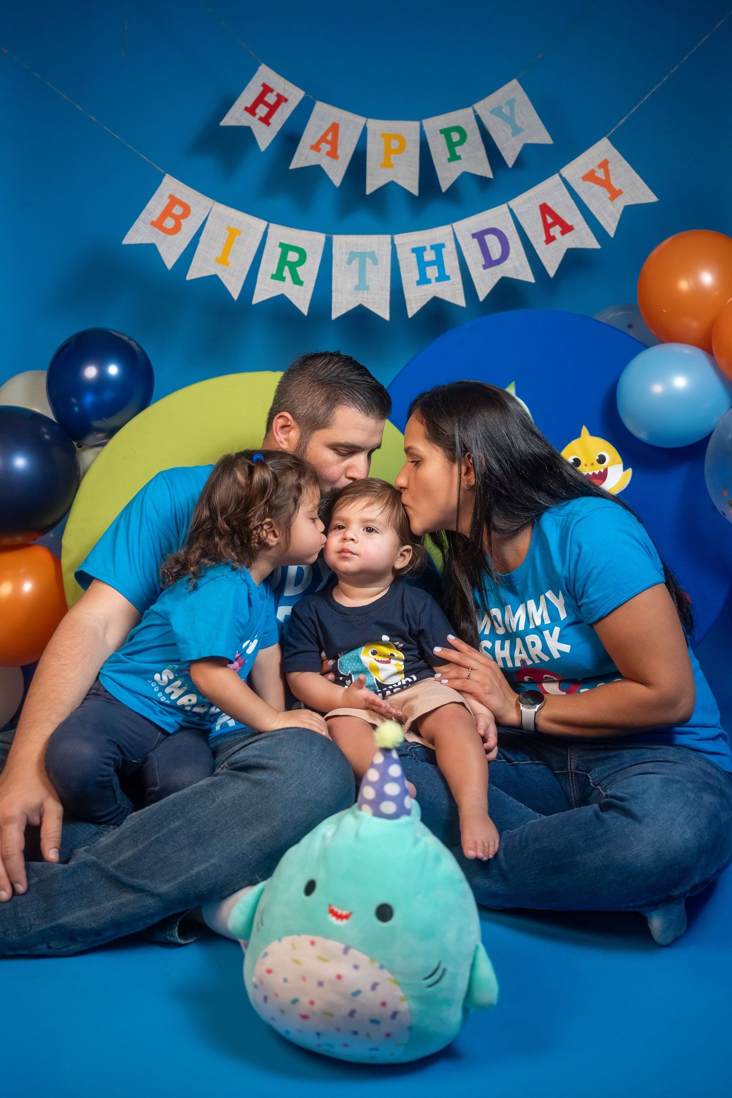 Parents cuddling their child during a first birthday family portrait session.