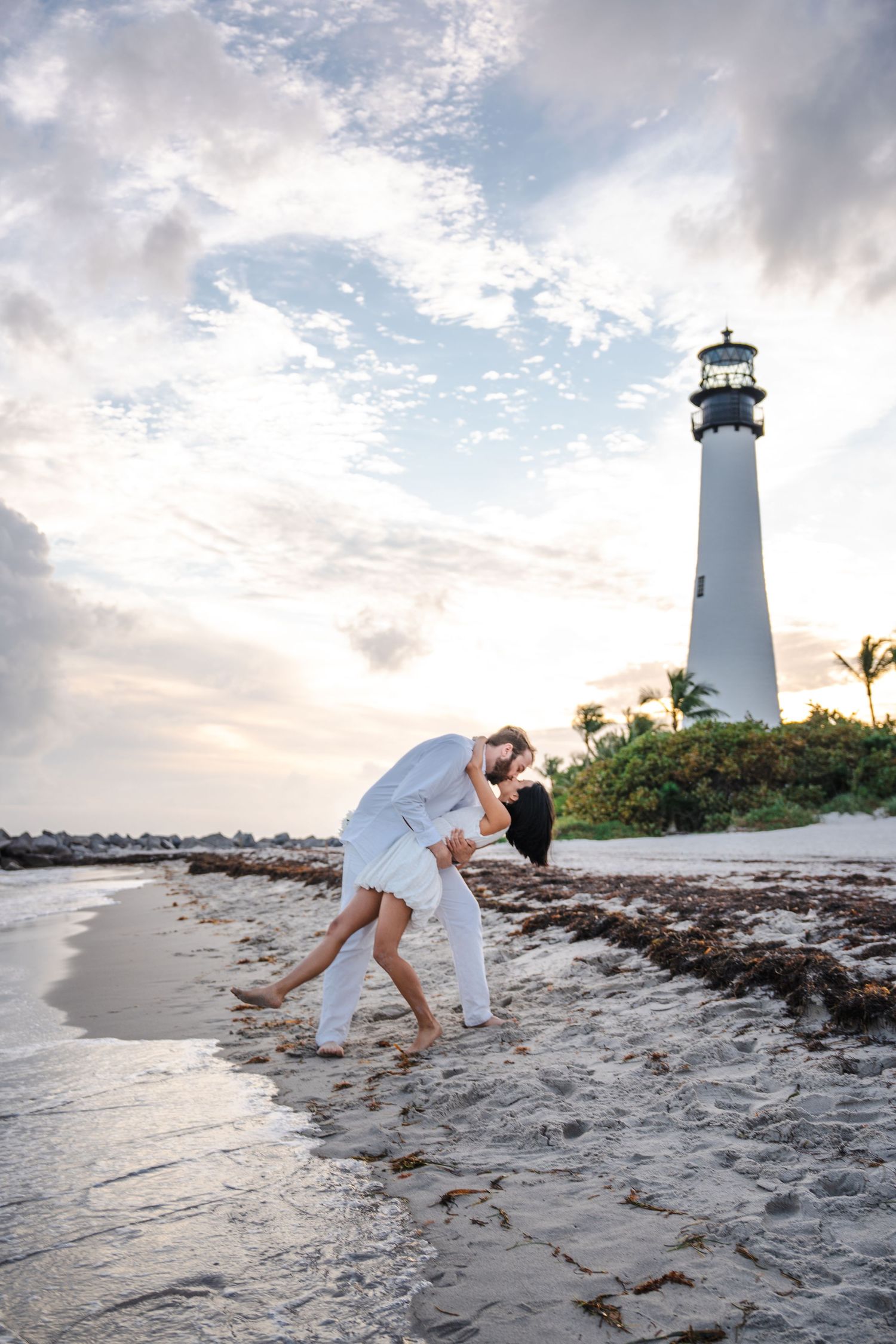 Playful engagement moment near the Bill Baggs lighthouse during a beach photo session.