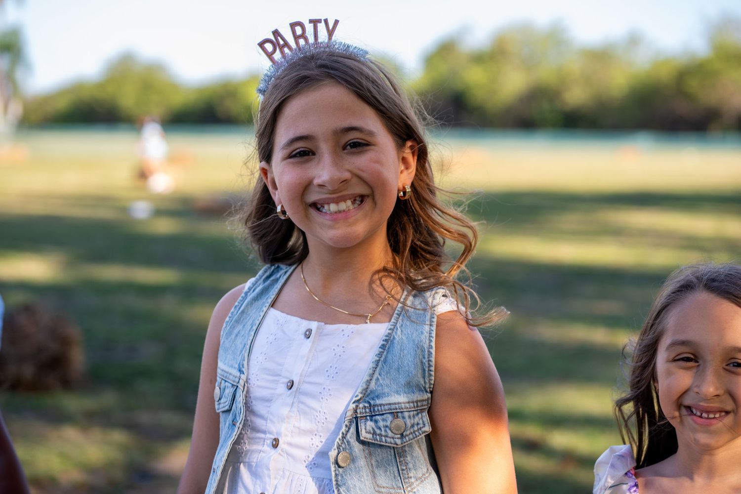 Birthday girl in tiara smiling in sunflower field, Miami event portrait session.
