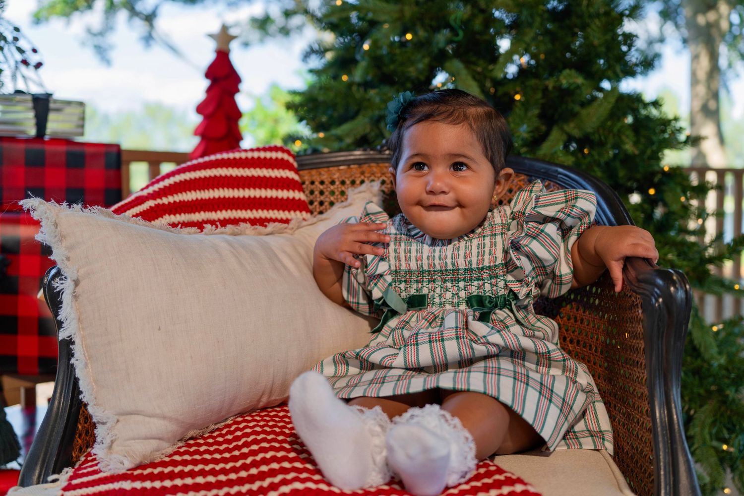 Adorable baby holiday mini session in Hollywood, FL – cozy Christmas setup with festive pillows and twinkling lights.