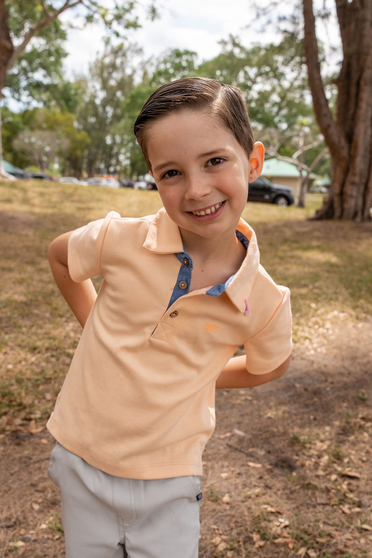 Playful portrait of a young boy smiling outdoors during a South Florida family event.