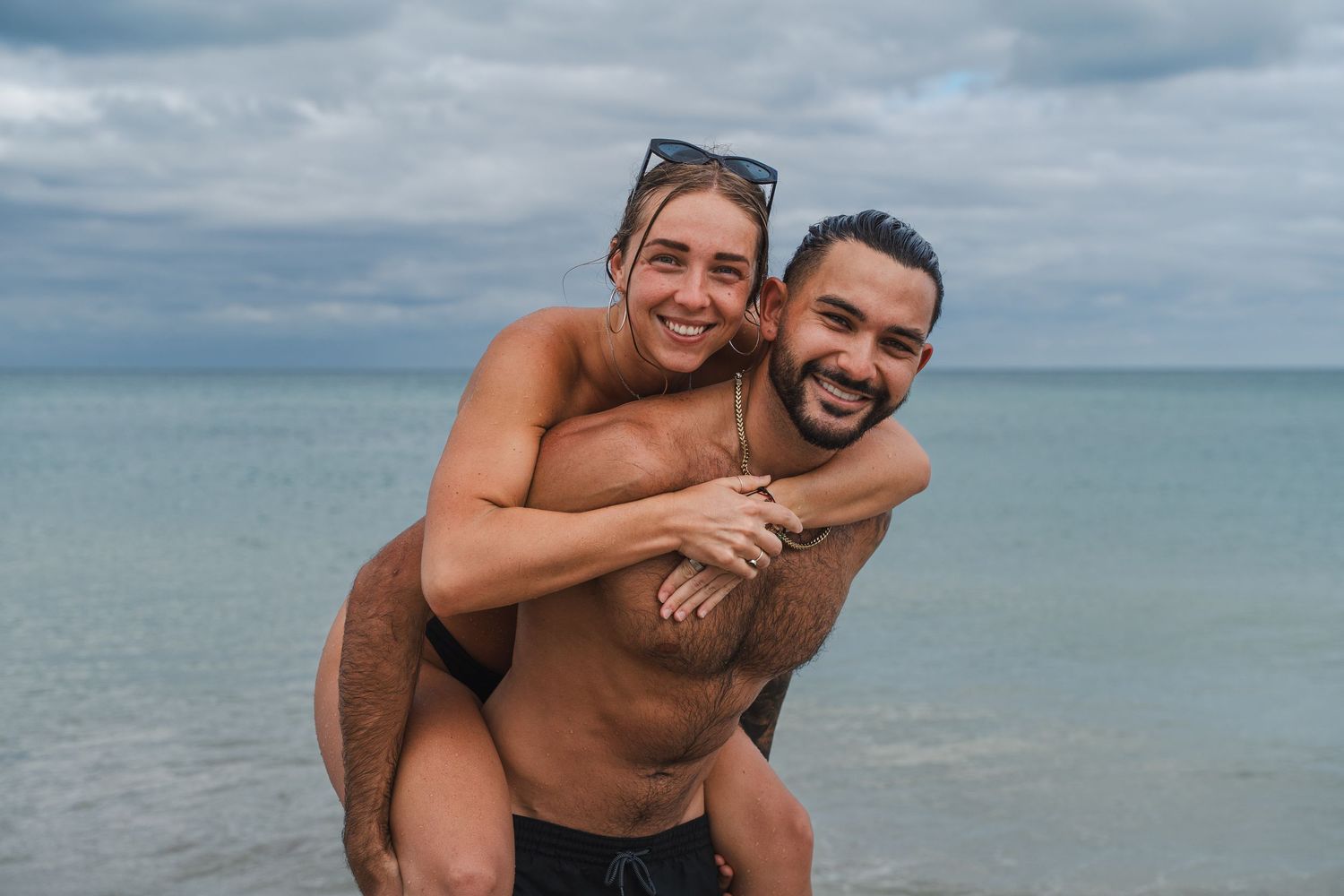 Playful couple portrait of two partners laughing together in the ocean during a relaxed beach session in South Florida.