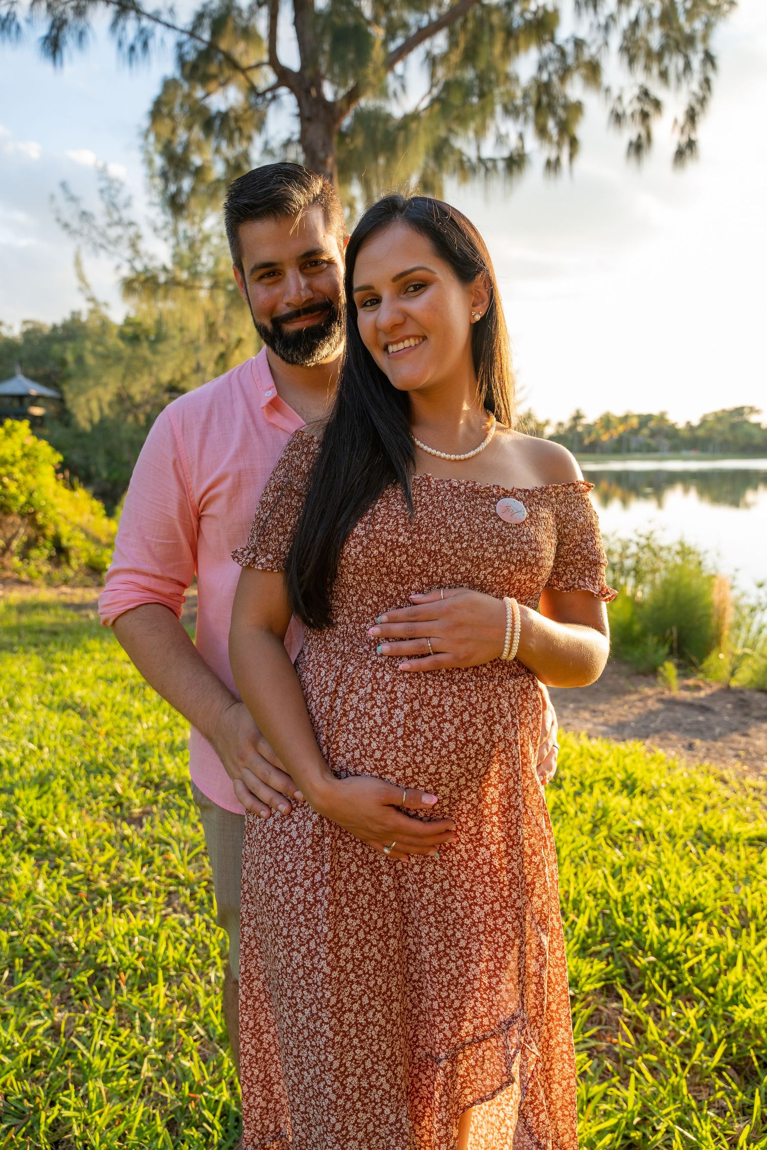 Outdoor maternity portrait of an expecting couple standing together in golden-hour light in South Florida.