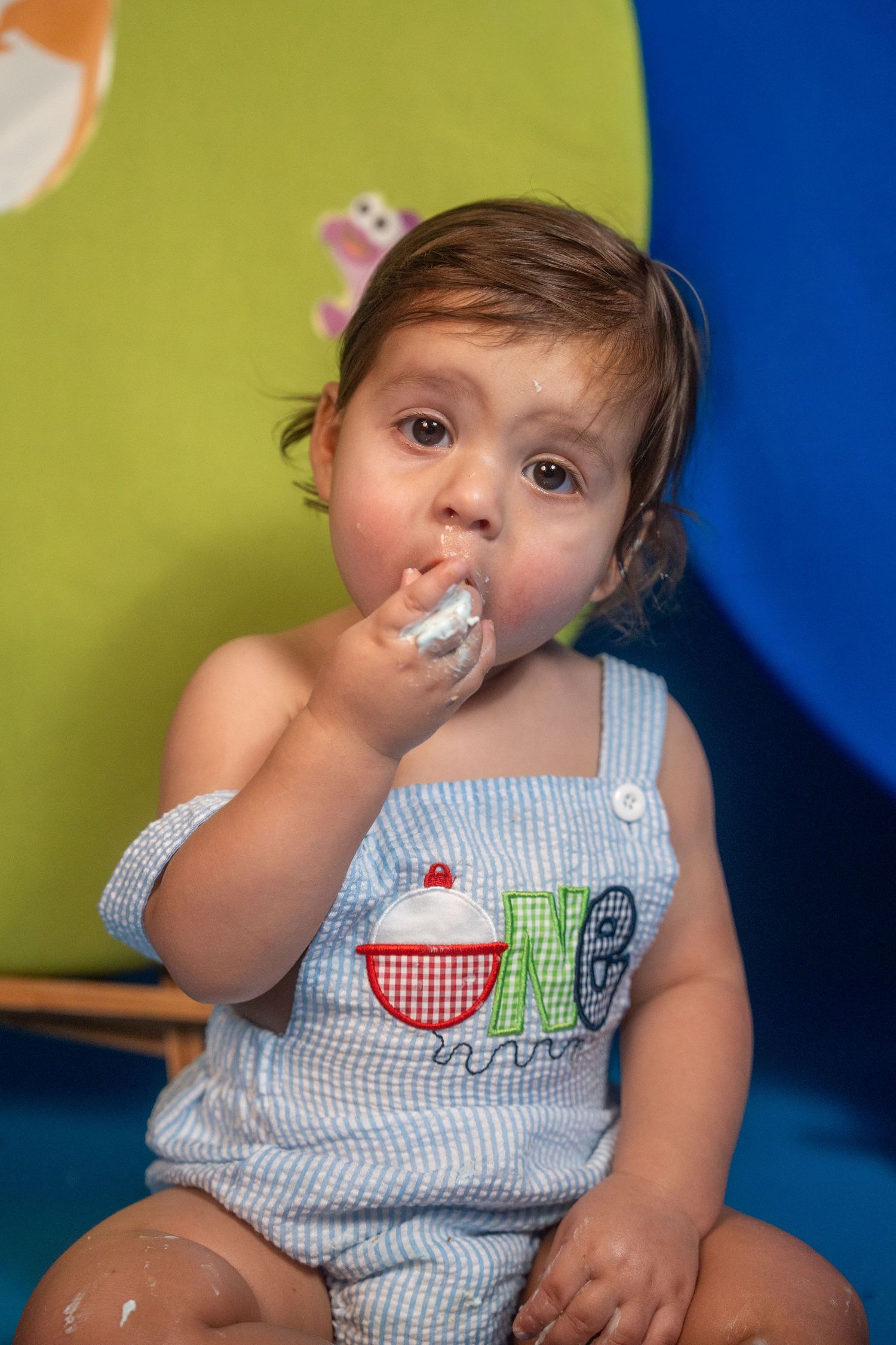 Close-up portrait of a toddler enjoying cake during a first birthday photo session.