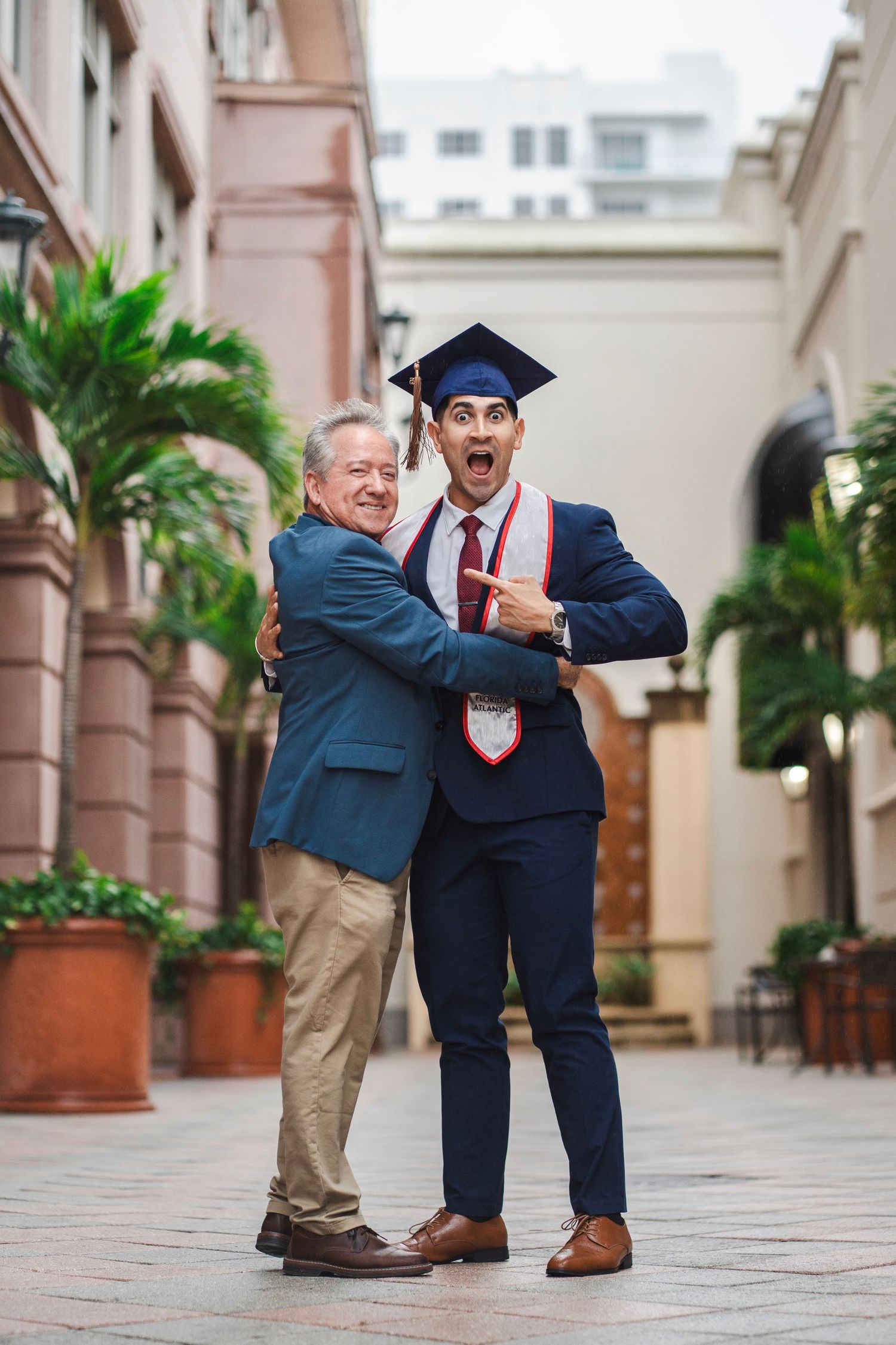 FAU graduate portrait with a parent, photographed in a South Florida campus courtyard. Father son photo