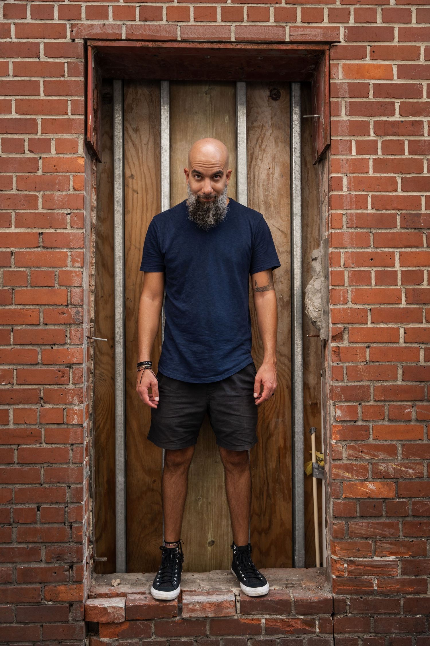 Urban portrait in Wynwood, Miami, FL – bold and moody headshot of a man standing against a rustic brick wall.