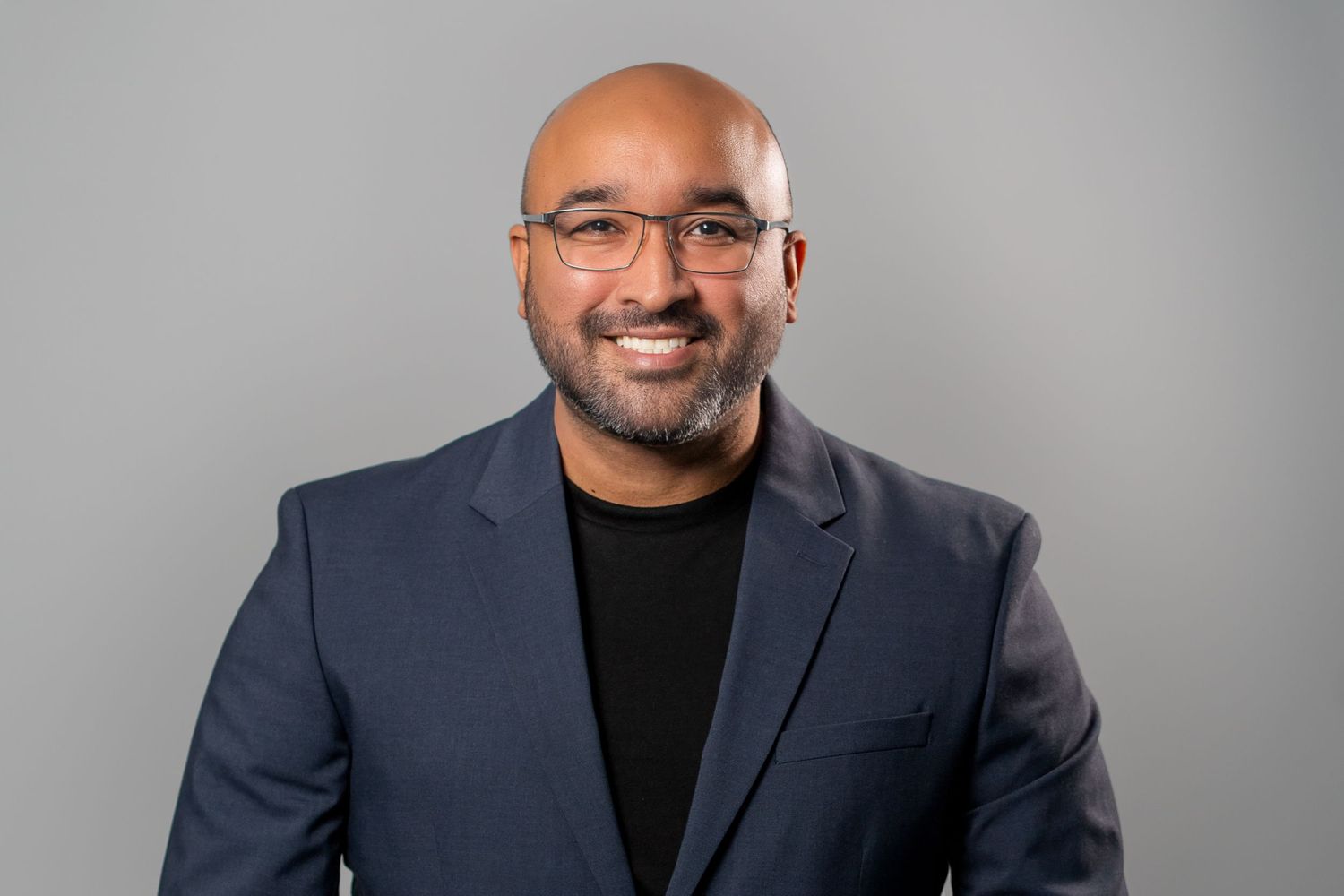 Bald man in blazer smiling during studio professional headshot session