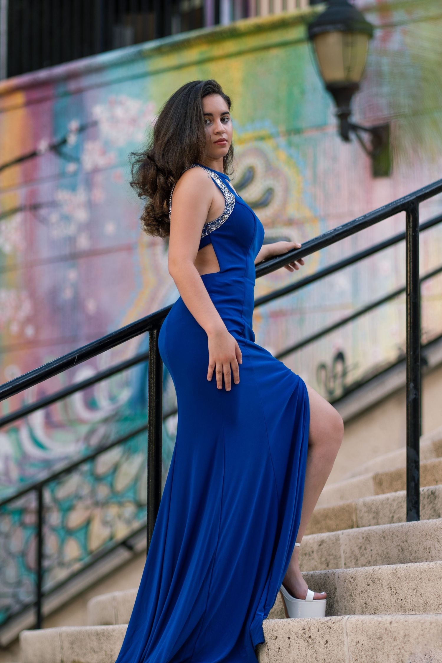 Vibrant urban portrait session in Miami, FL – woman in a striking blue gown poses against a colorful graffiti wall.