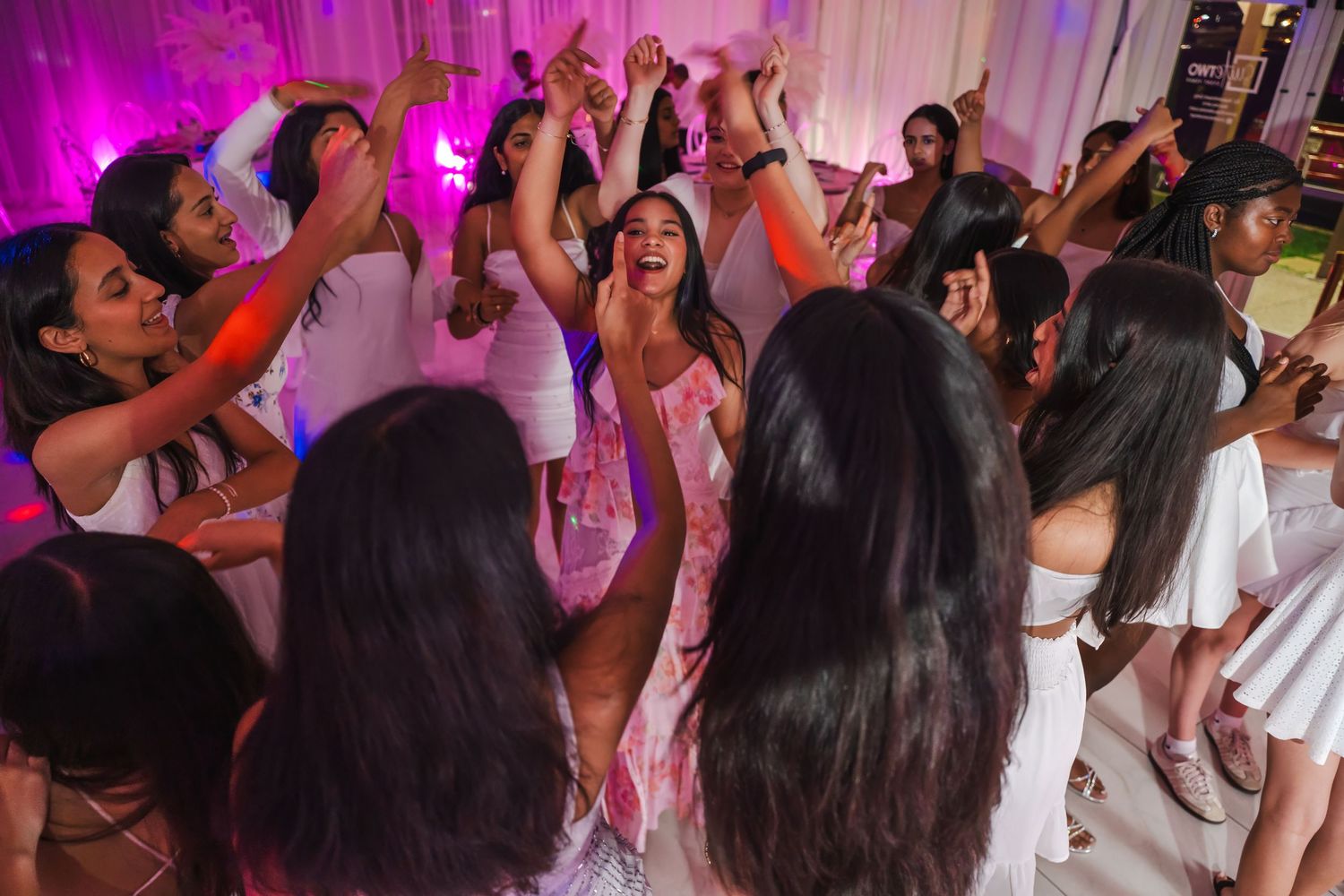 Birthday girl dancing with friends under pink uplighting during a Sweet 16 party in Miami.