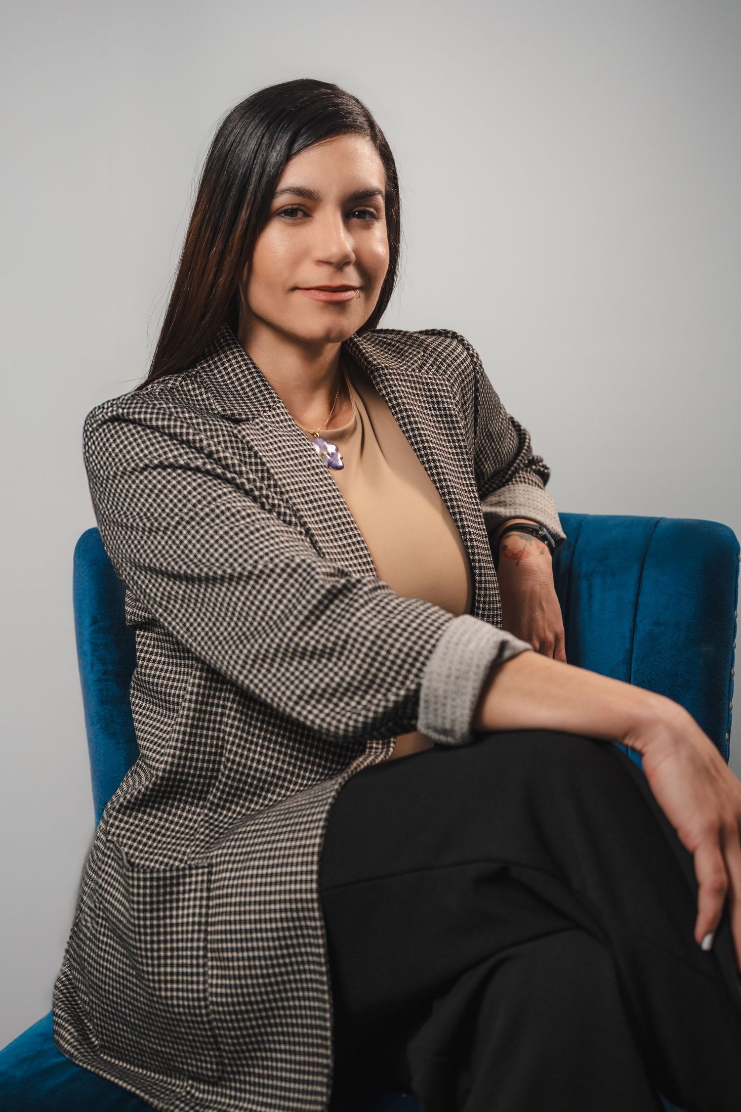 Woman in a checkered blazer seated on a modern blue chair for a branding session.
