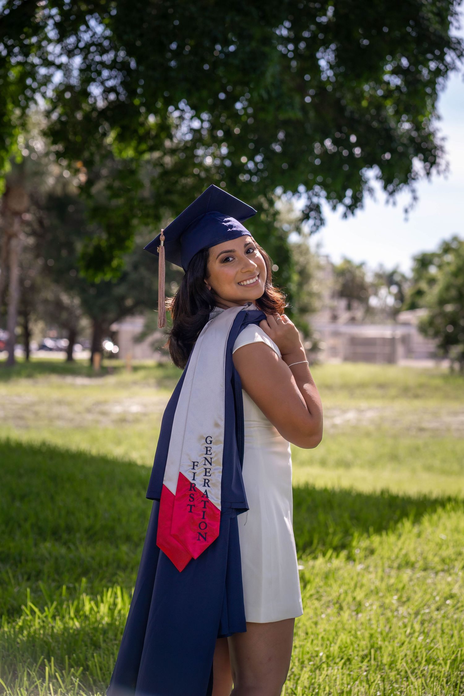 Graduation portrait of FAU student smiling in white dress and cap outdoors