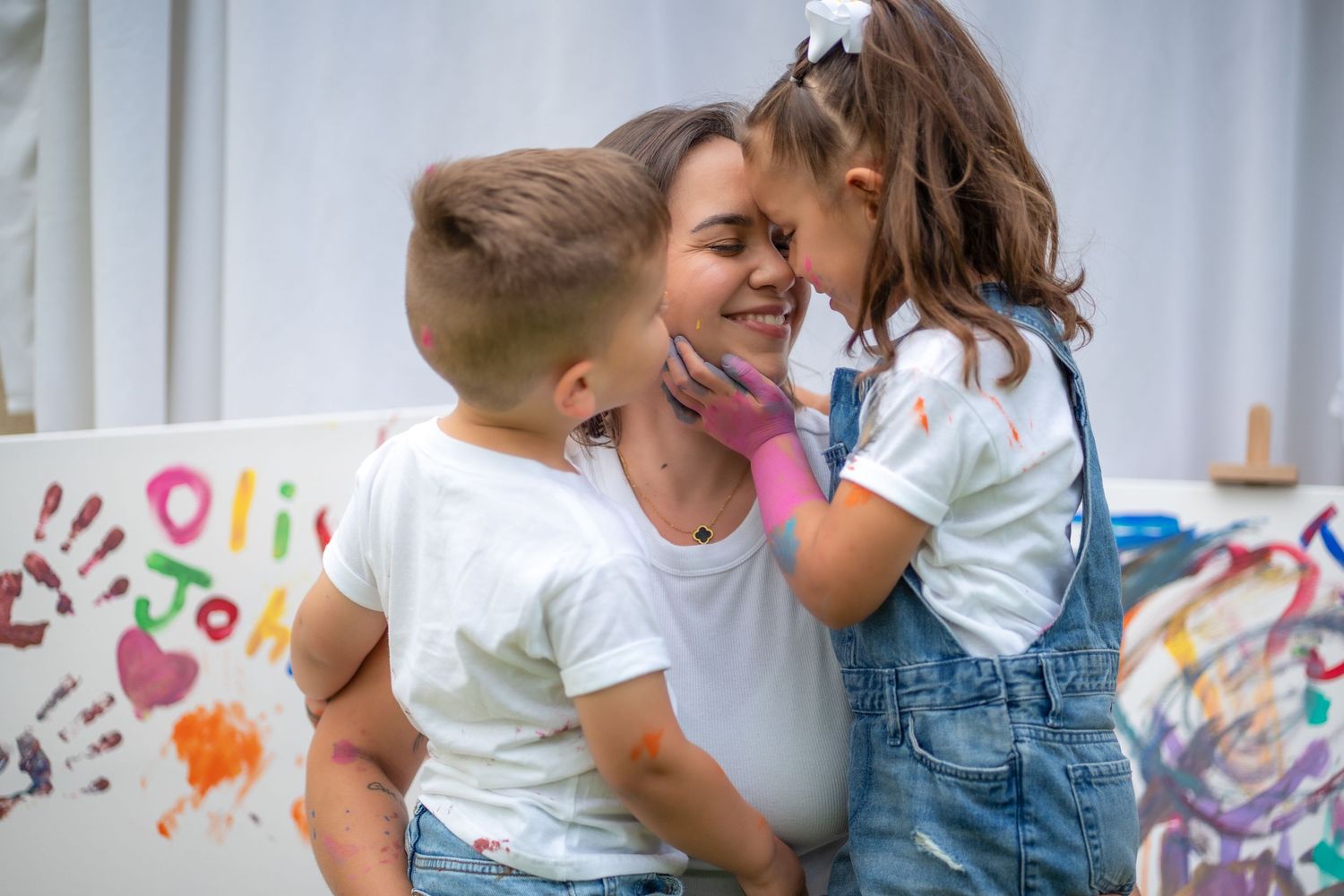 Sweet moment of mom and daughters giggling during an outdoor creative family session.