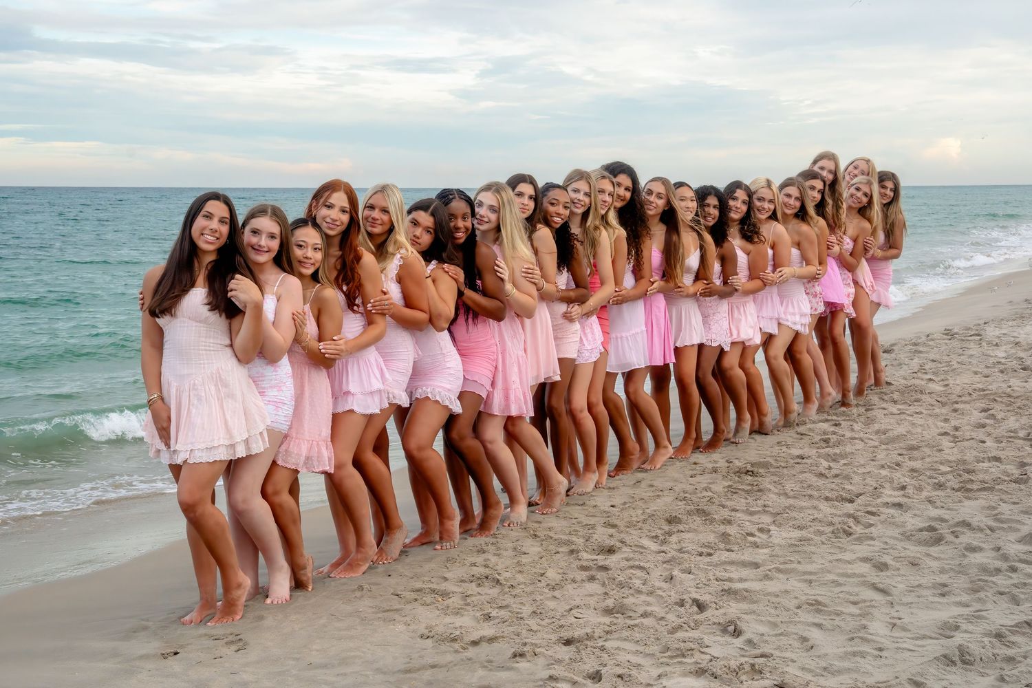 Cheer squad lined up along the shoreline in matching pink dresses during a South Florida beach photo session.
