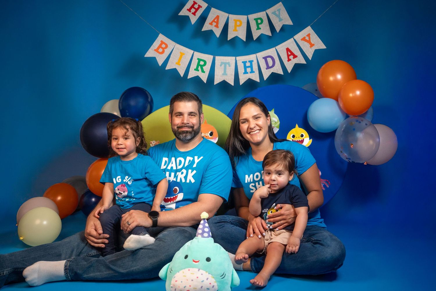 Family portrait celebrating a child’s first birthday in a colorful studio setup.