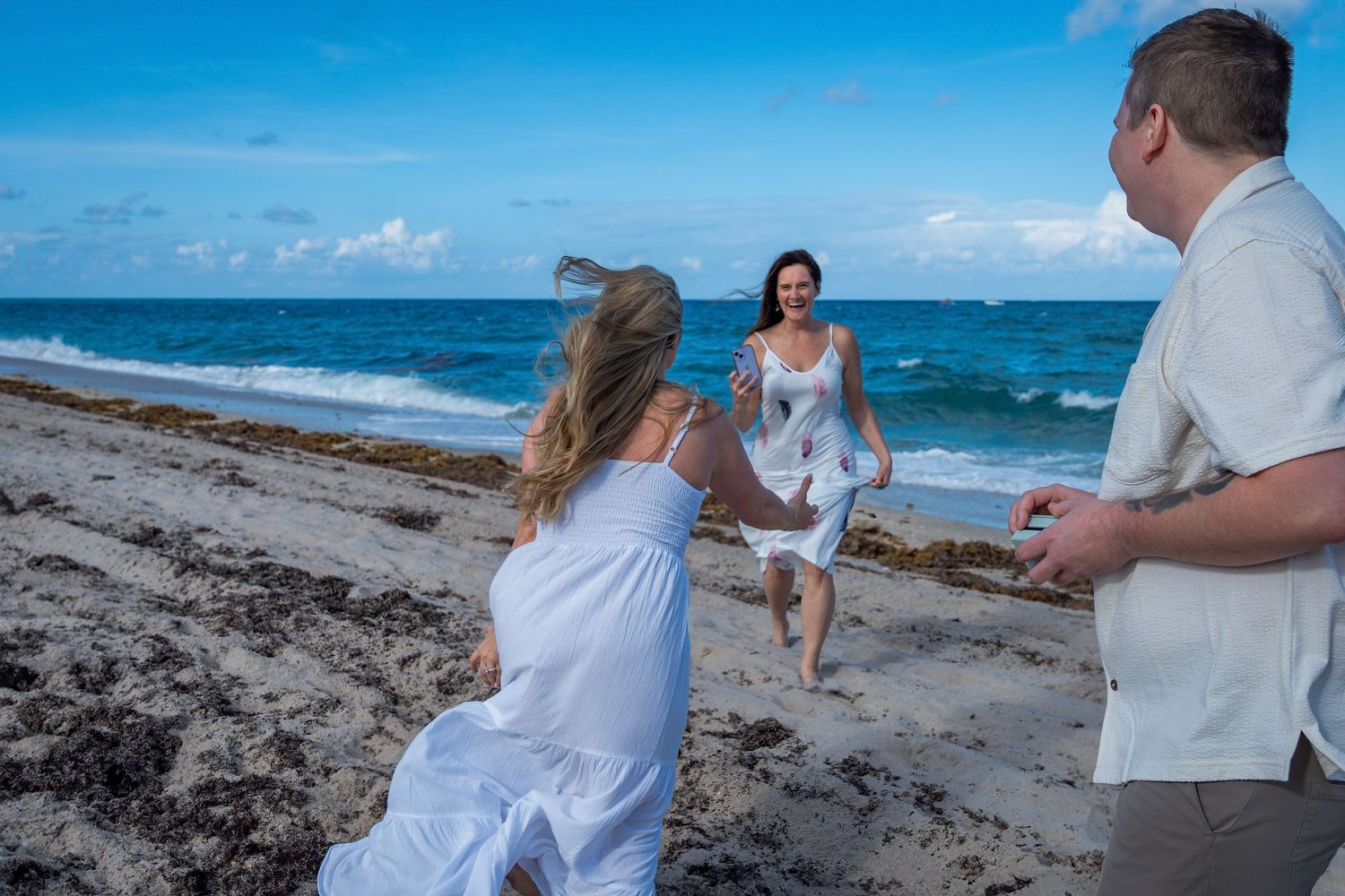 Candid post-proposal moment capturing raw emotion and excitement on the beach.