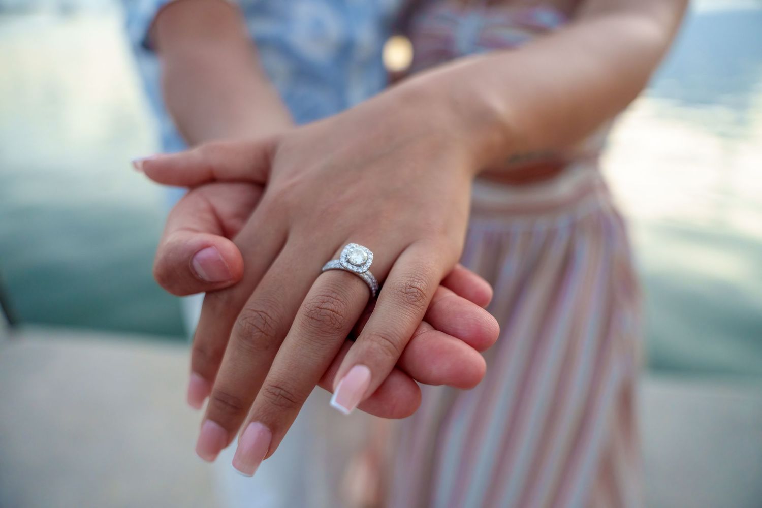 Close-up of elegant engagement ring on bride-to-be’s hand, captured in soft focus with ocean waves in Key Biscayne, FL.