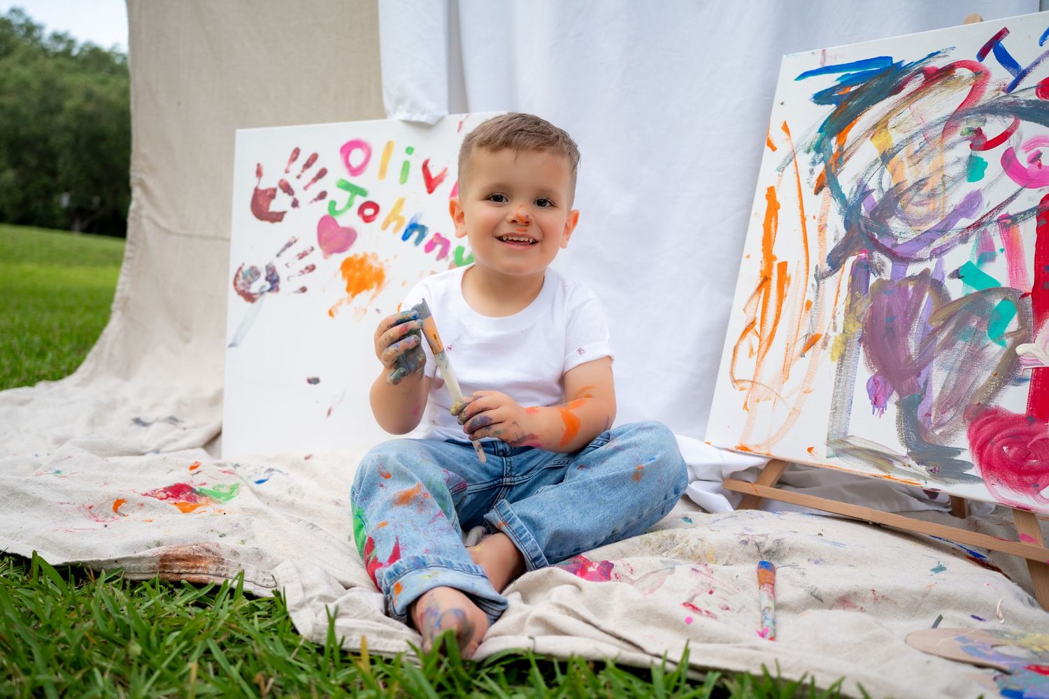 Young boy posing with paint-covered hands and a big grin during a lifestyle family shoot.