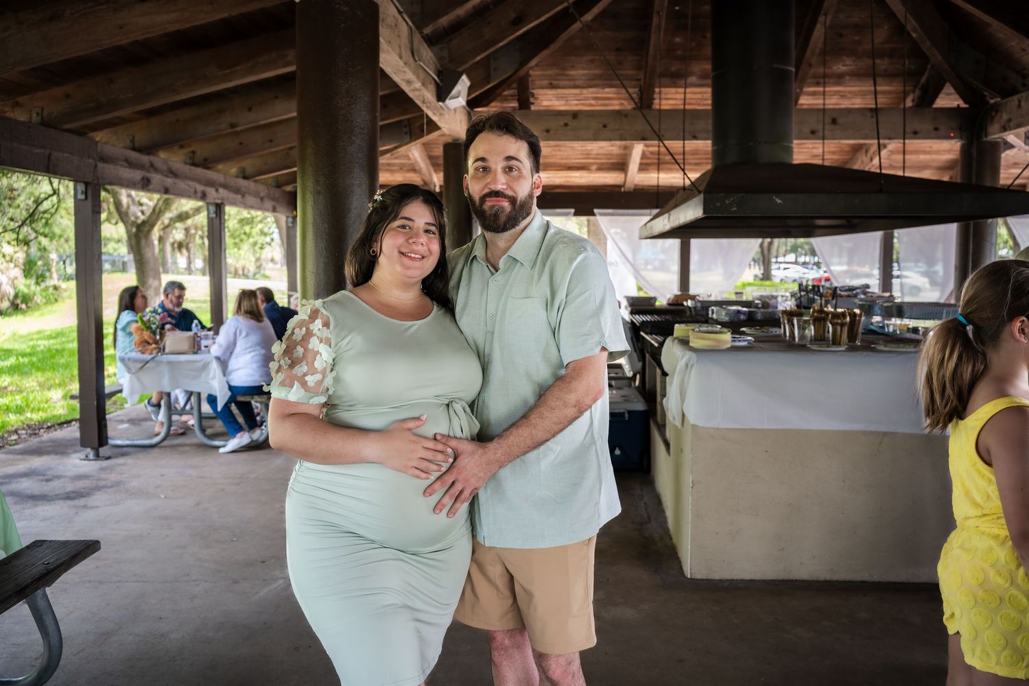 Expecting mother posing with her partner during a baby shower celebration at an outdoor venue in South Florida.