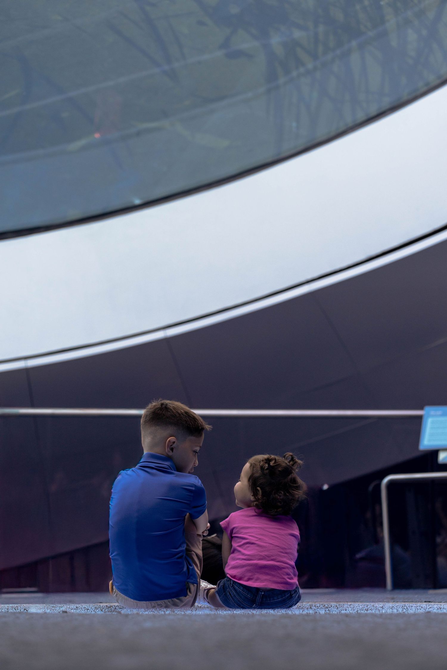 A heartwarming cousins moment captured inside Frost Museum with futuristic architecture serving as a unique backdrop.