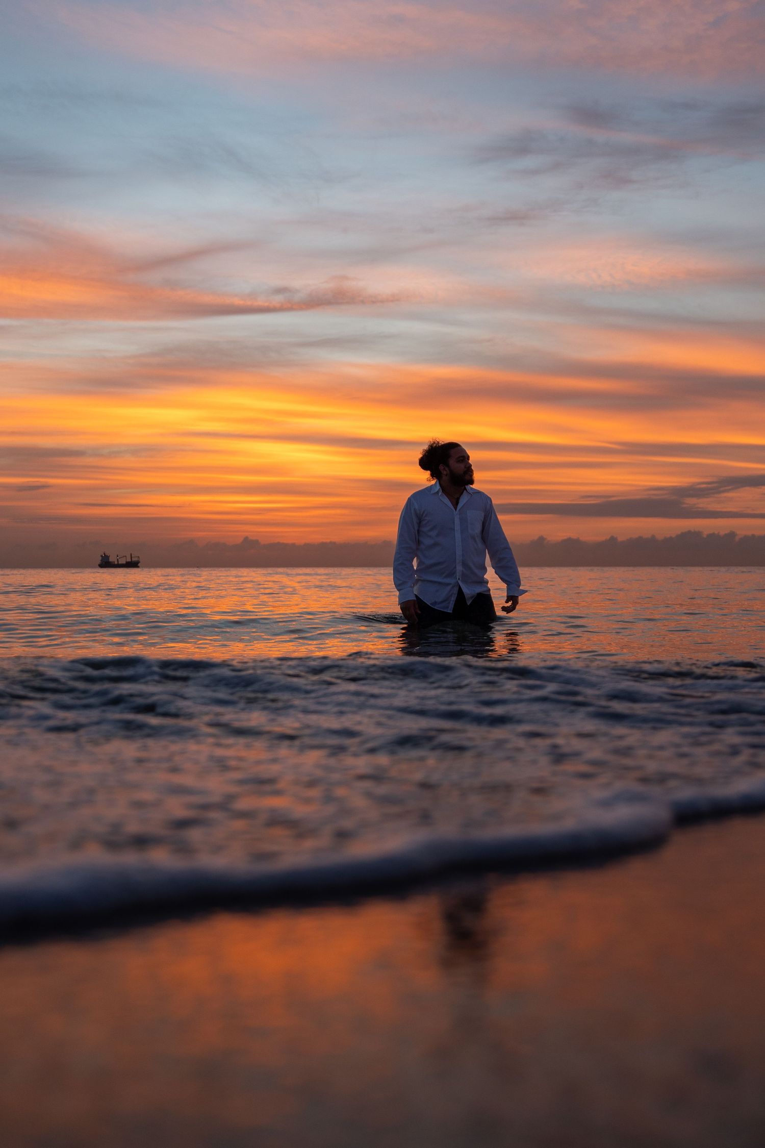Sunrise ocean portrait – a man stands waist-deep in the water, silhouetted against the warm Miami sky.