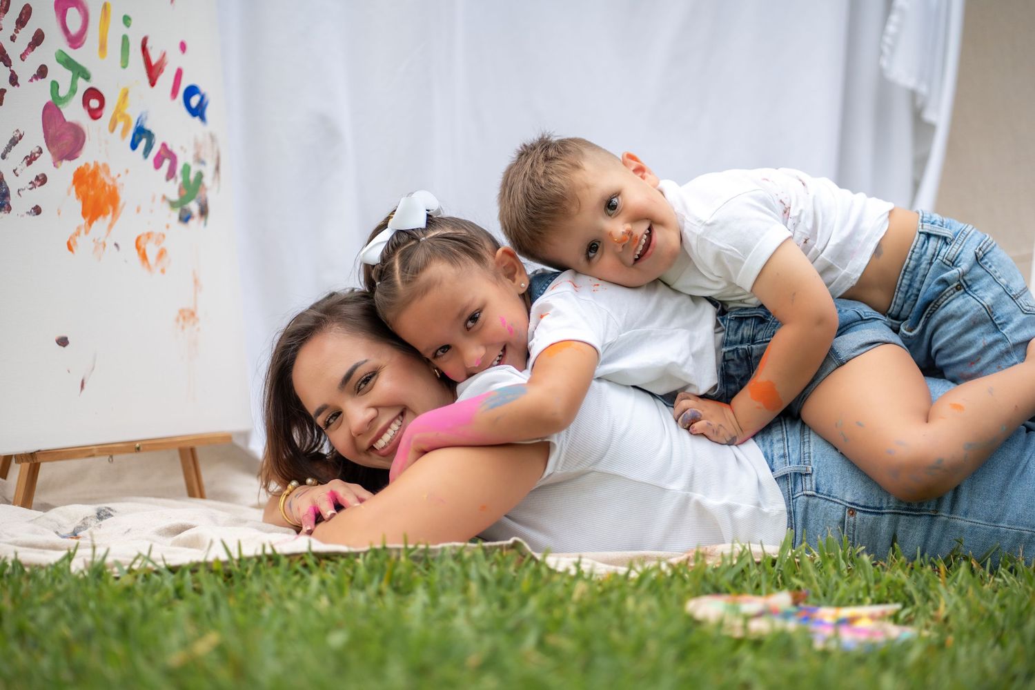 Kids laying on mom’s back, laughing and enjoying their painting activity in Miami.