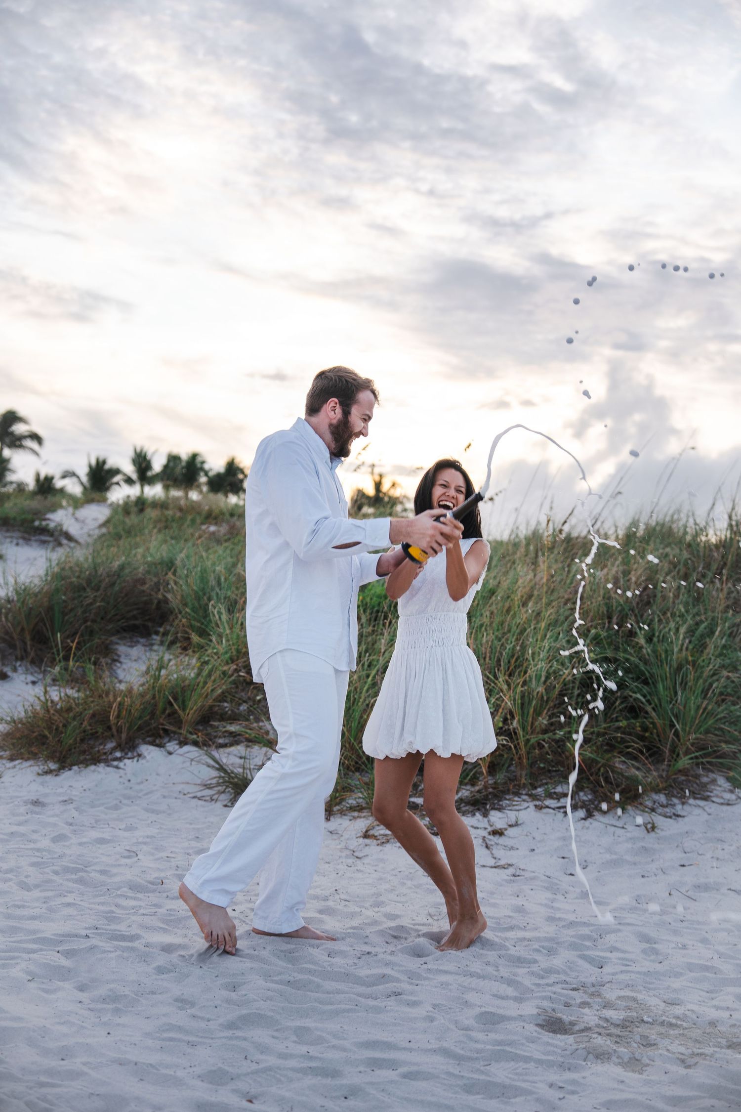 Couple walking together on the beach during a Bill Baggs engagement session at sunset.