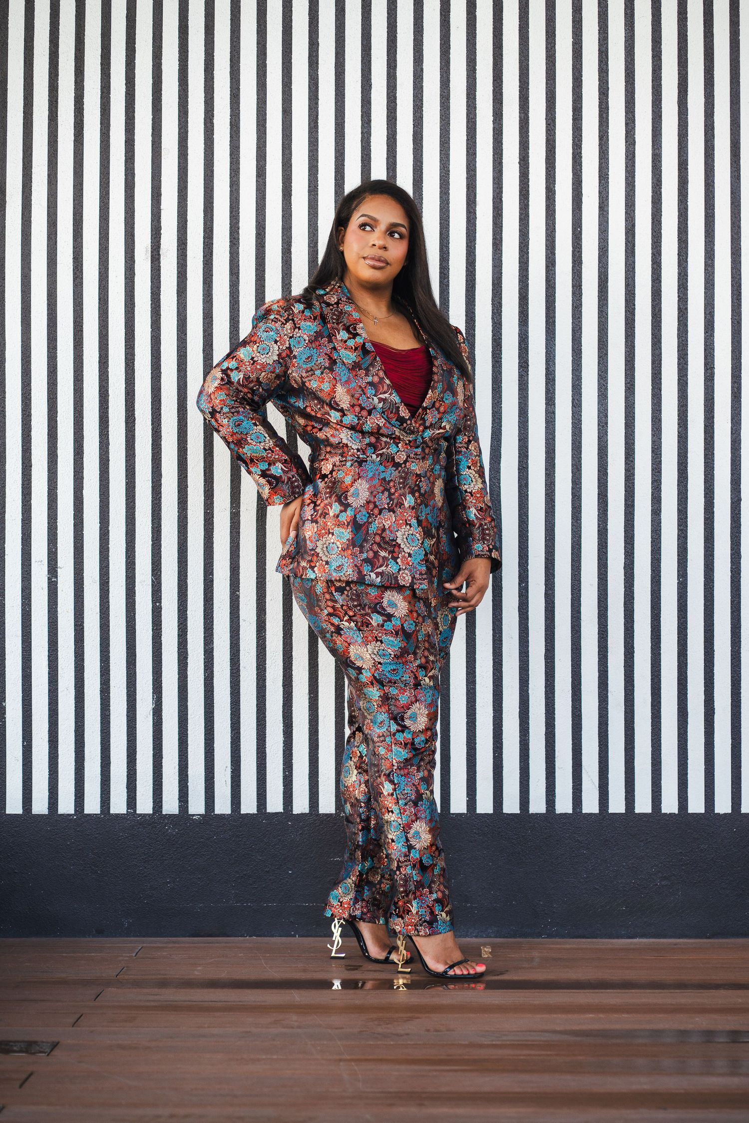 Full-body branding portrait of a scholarship coach and entrepreneur against a modern striped backdrop.