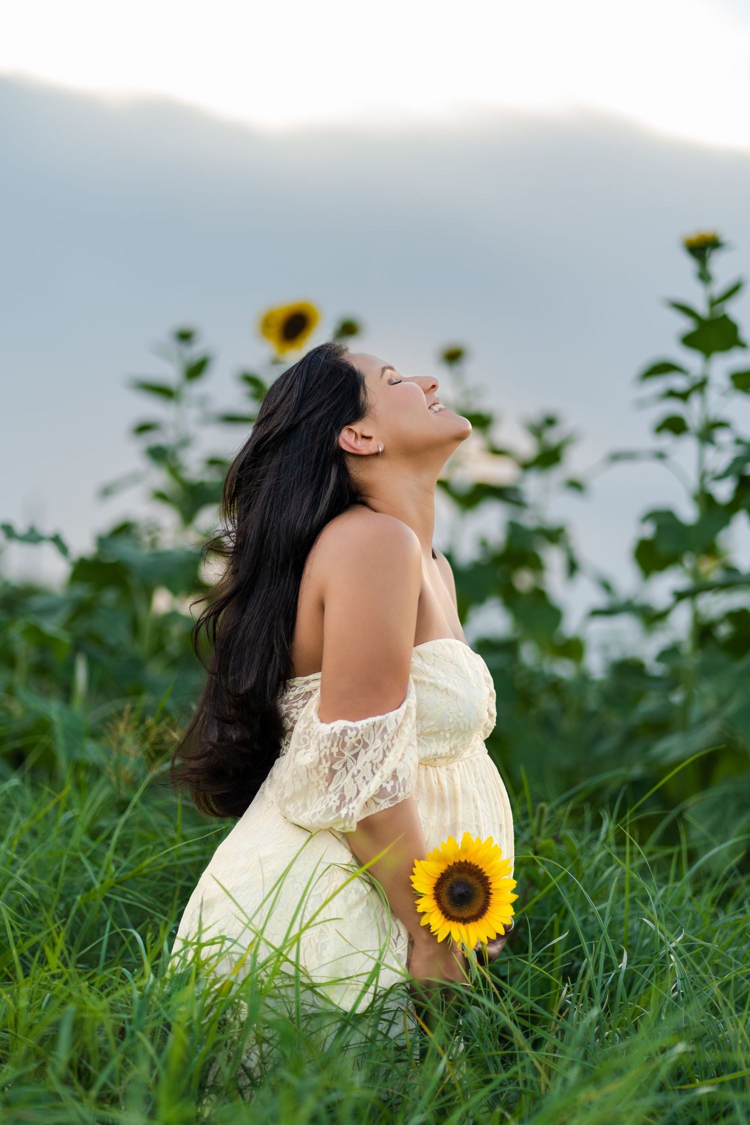 Sunset maternity session in Homestead, FL, featuring glowing mom-to-be walking through a vibrant sunflower field.