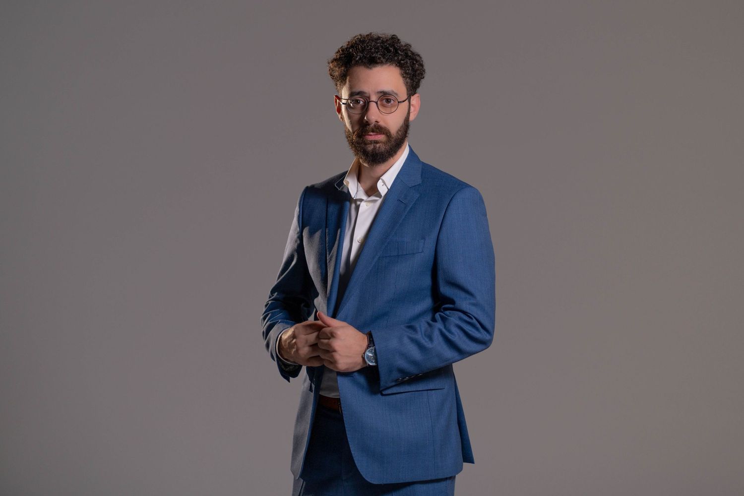 Man in blue suit adjusting jacket during professional studio portrait
Man in blue suit smiling during studio portrait session