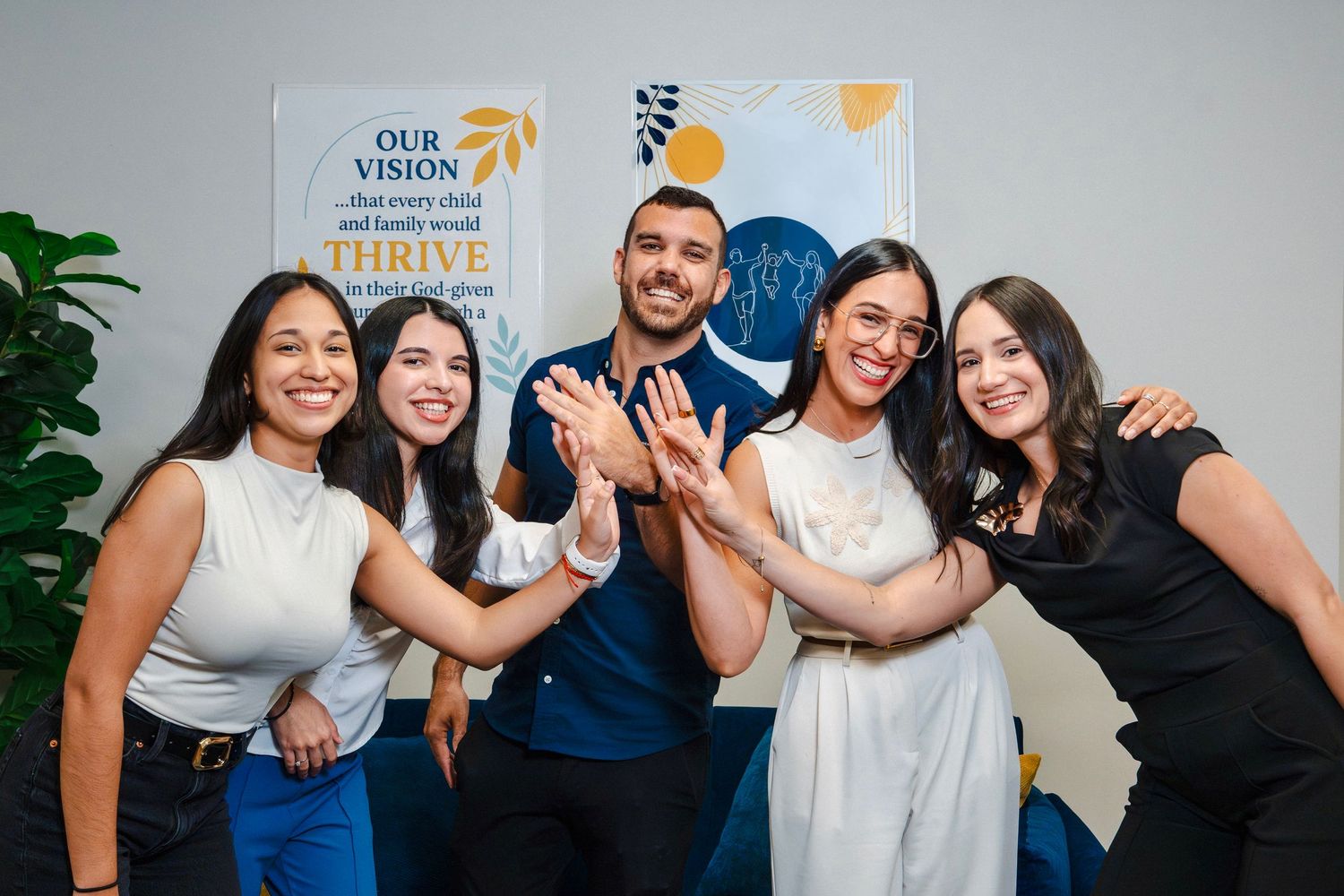 Chiropractic team gathered together in clinic, smiling and celebrating in front of branded wall signage during branding session