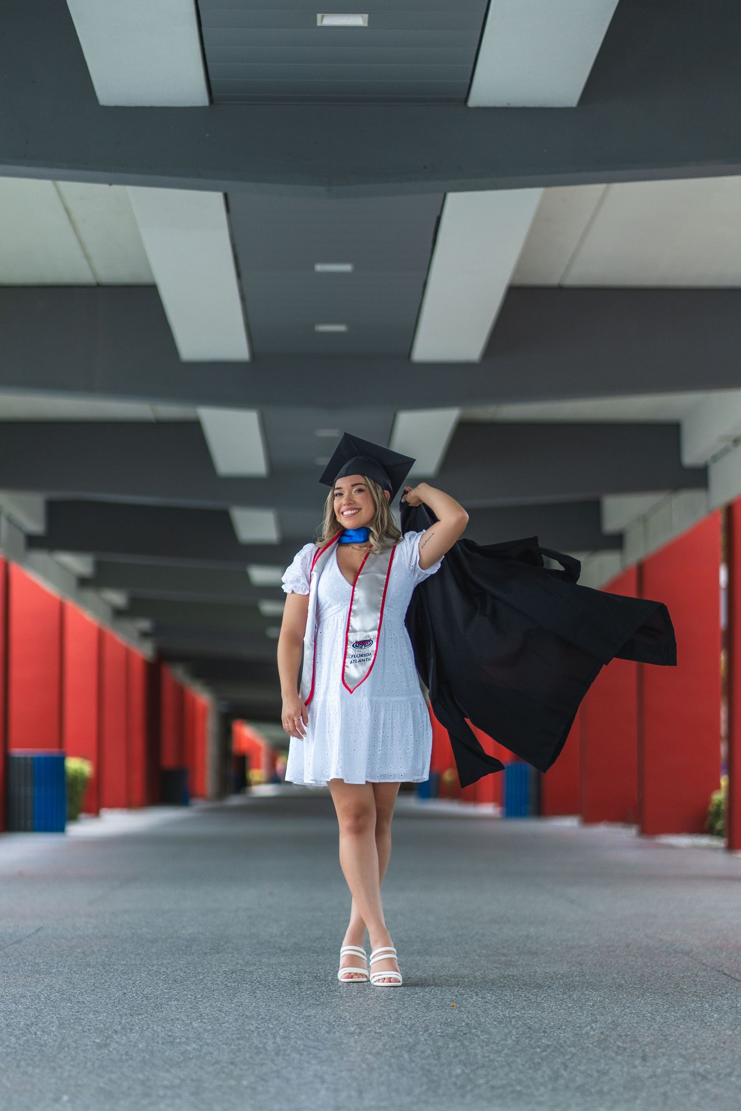 FAU graduate flips her gown over her shoulder, celebrating a milestone moment in Florida Atlantic University’s modern architecture.