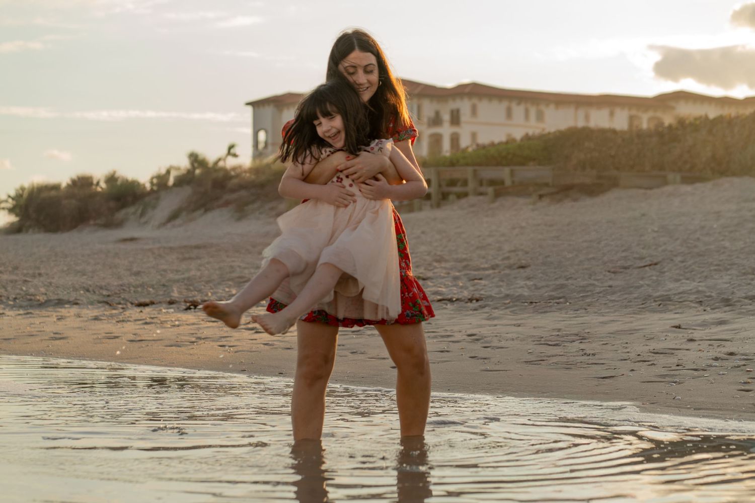 Mother-daughter beach moment in Delray Beach, FL – playful embrace in the ocean water at sunset.