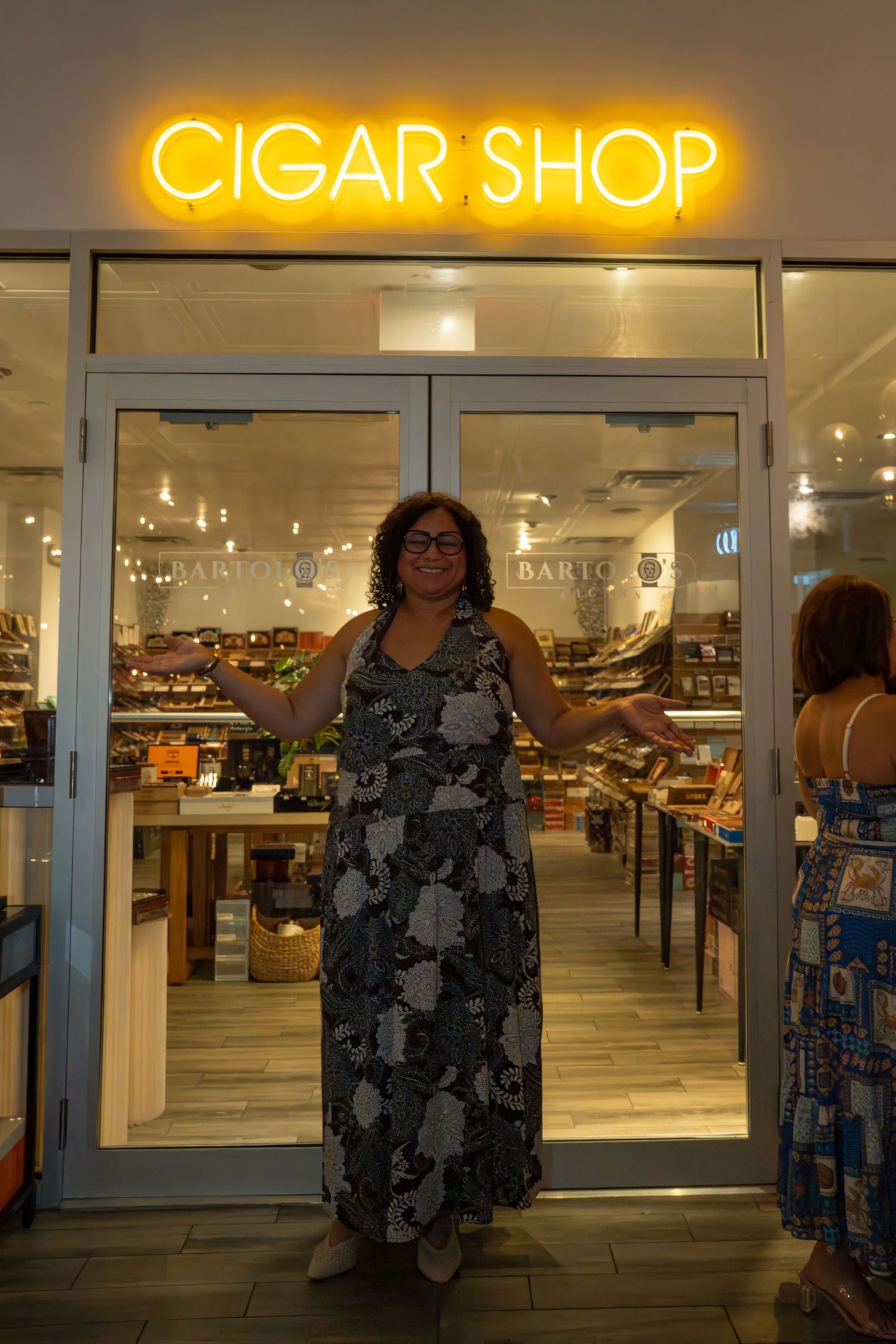 Owner of cafe standing at the entrance of Bartolo’s Wine Bar & Cigar Shop during the grand opening event in South Florida at night.