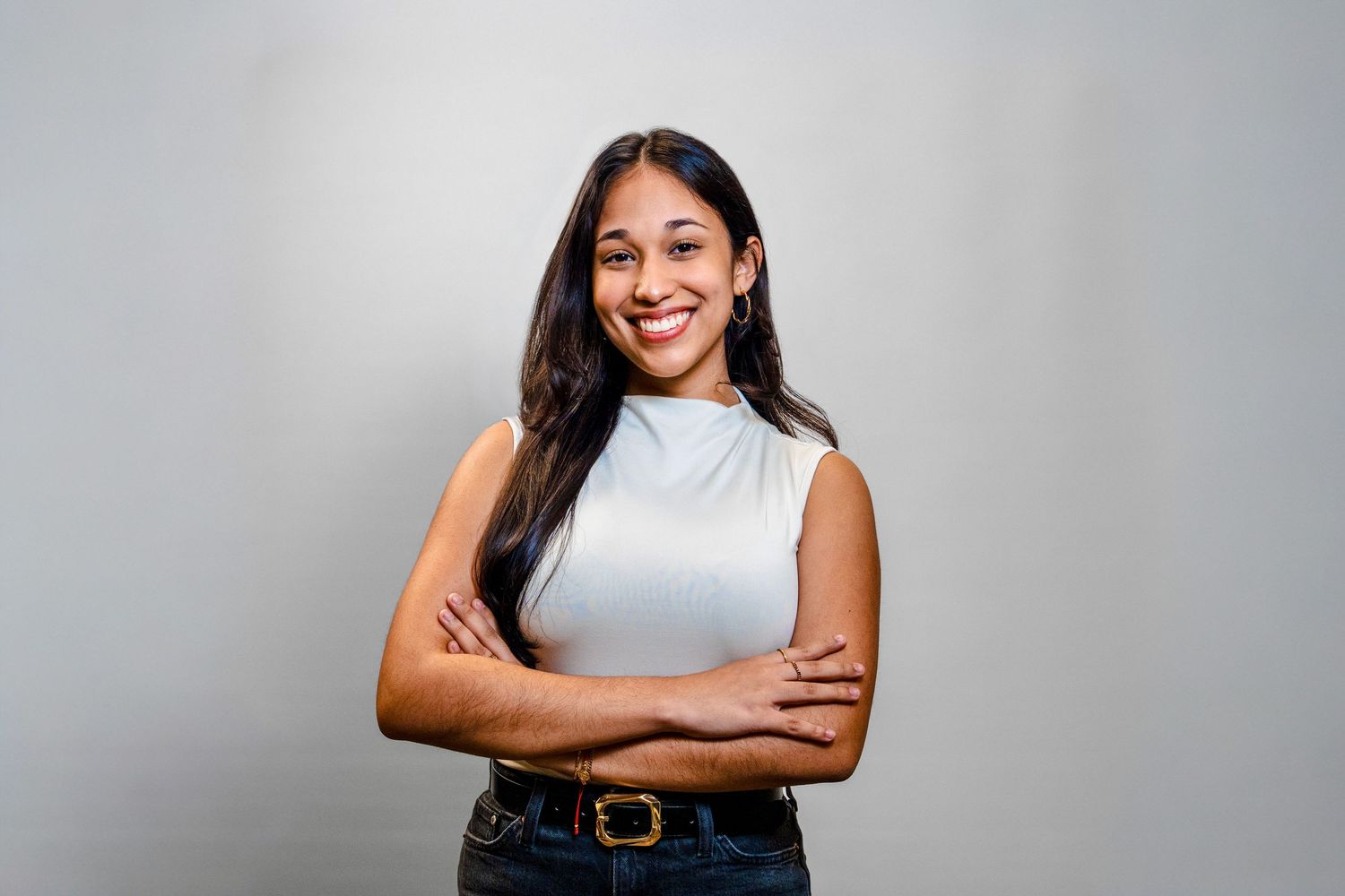 Professional headshot portrait of someone in a gray sleeveless top against a light background.