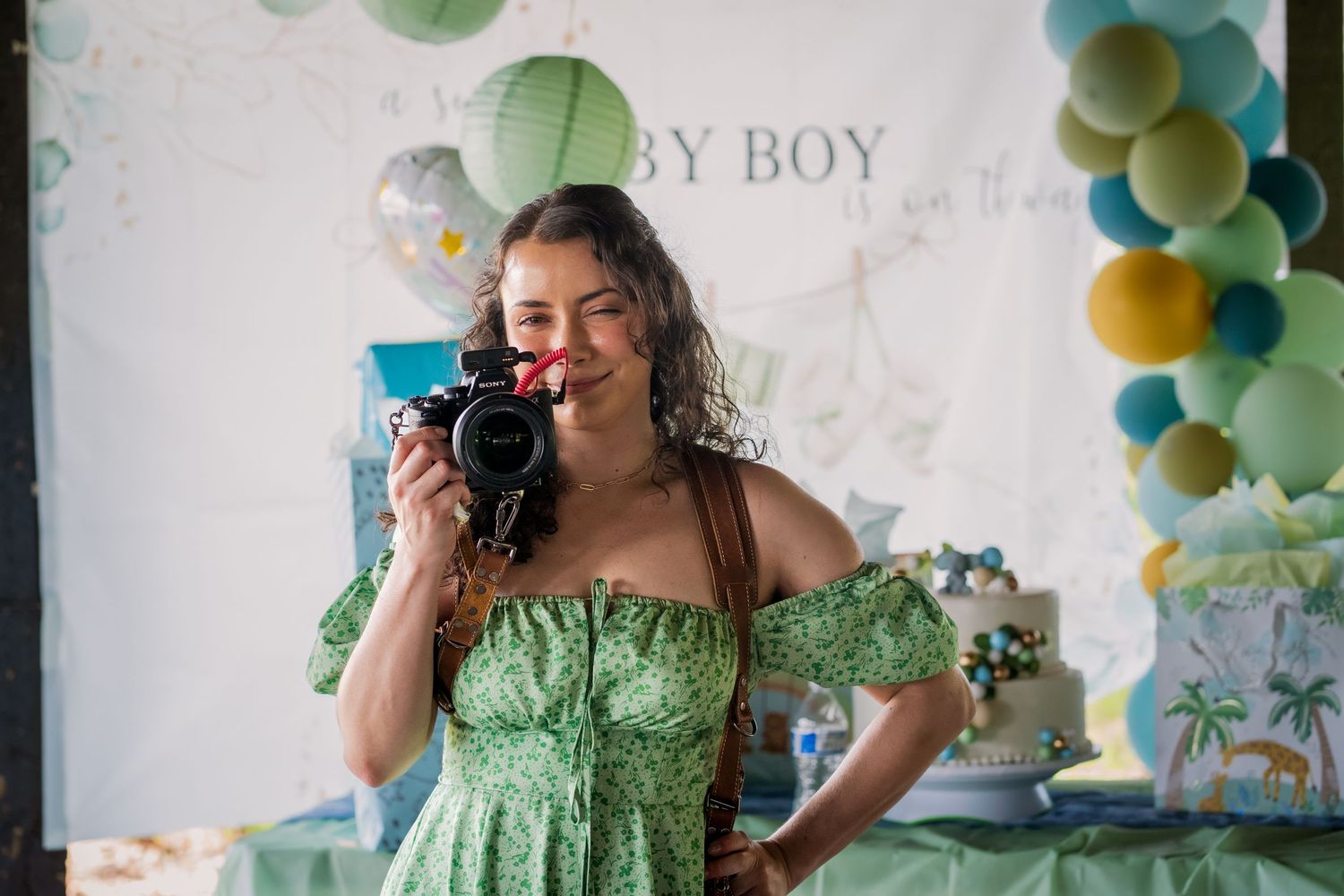 Woman holding camera at baby shower event in Miami with green and blue decor