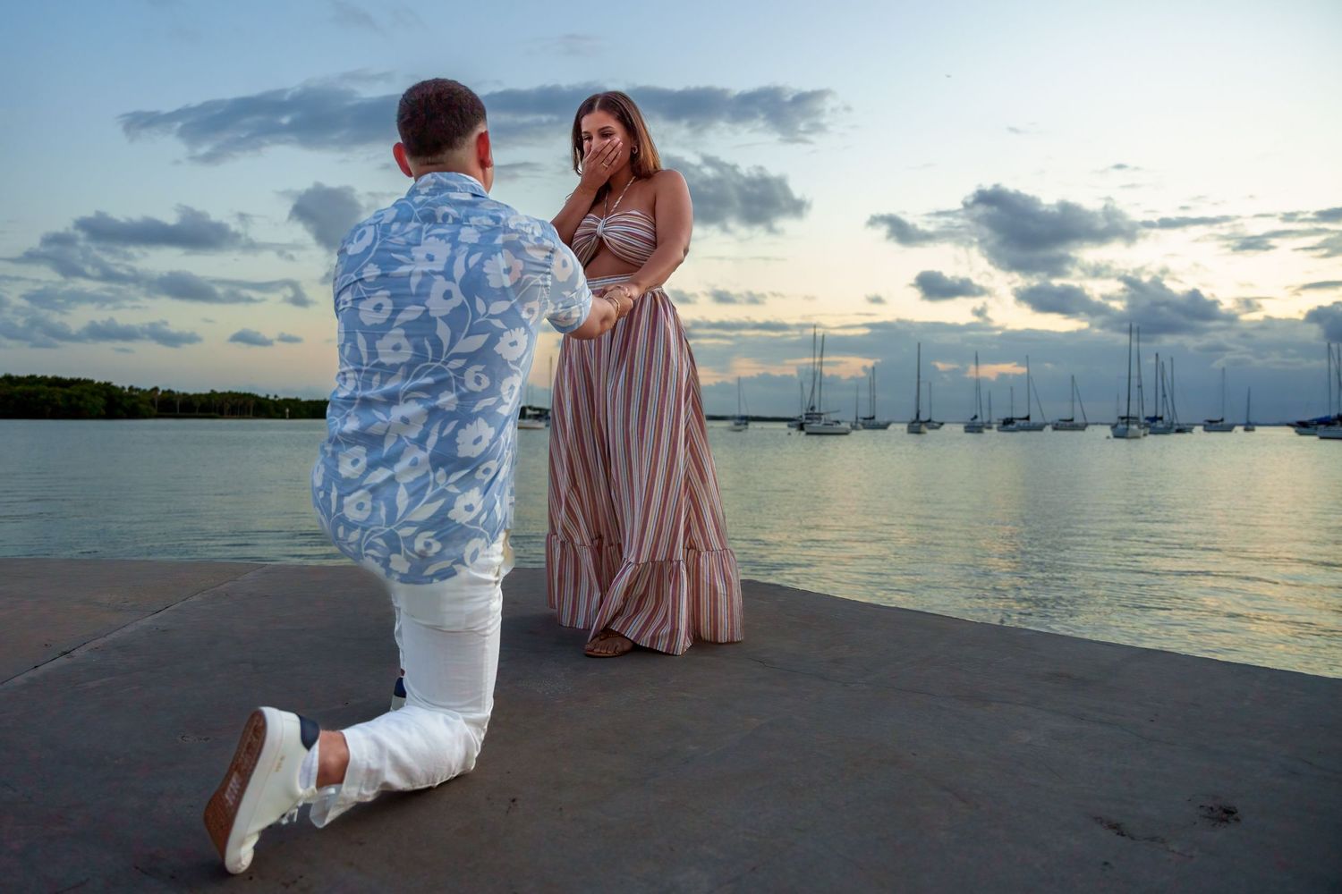 Romantic waterfront proposal in South Florida, capturing the groom-to-be’s heartfelt moment with a golden sunset glow.