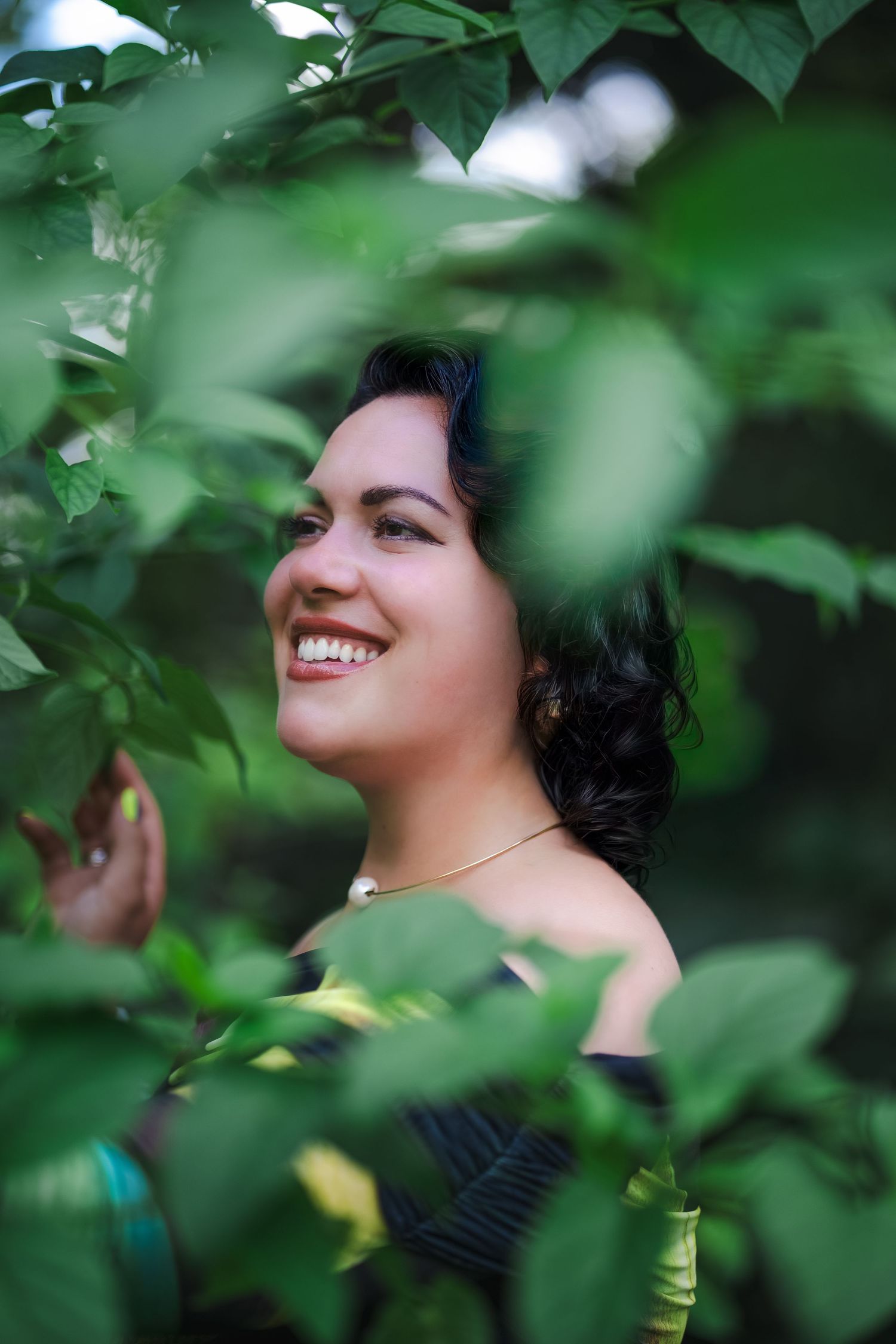 Candid branding photo of a woman smiling through foliage during a Fairchild Botanical Garden branding session.