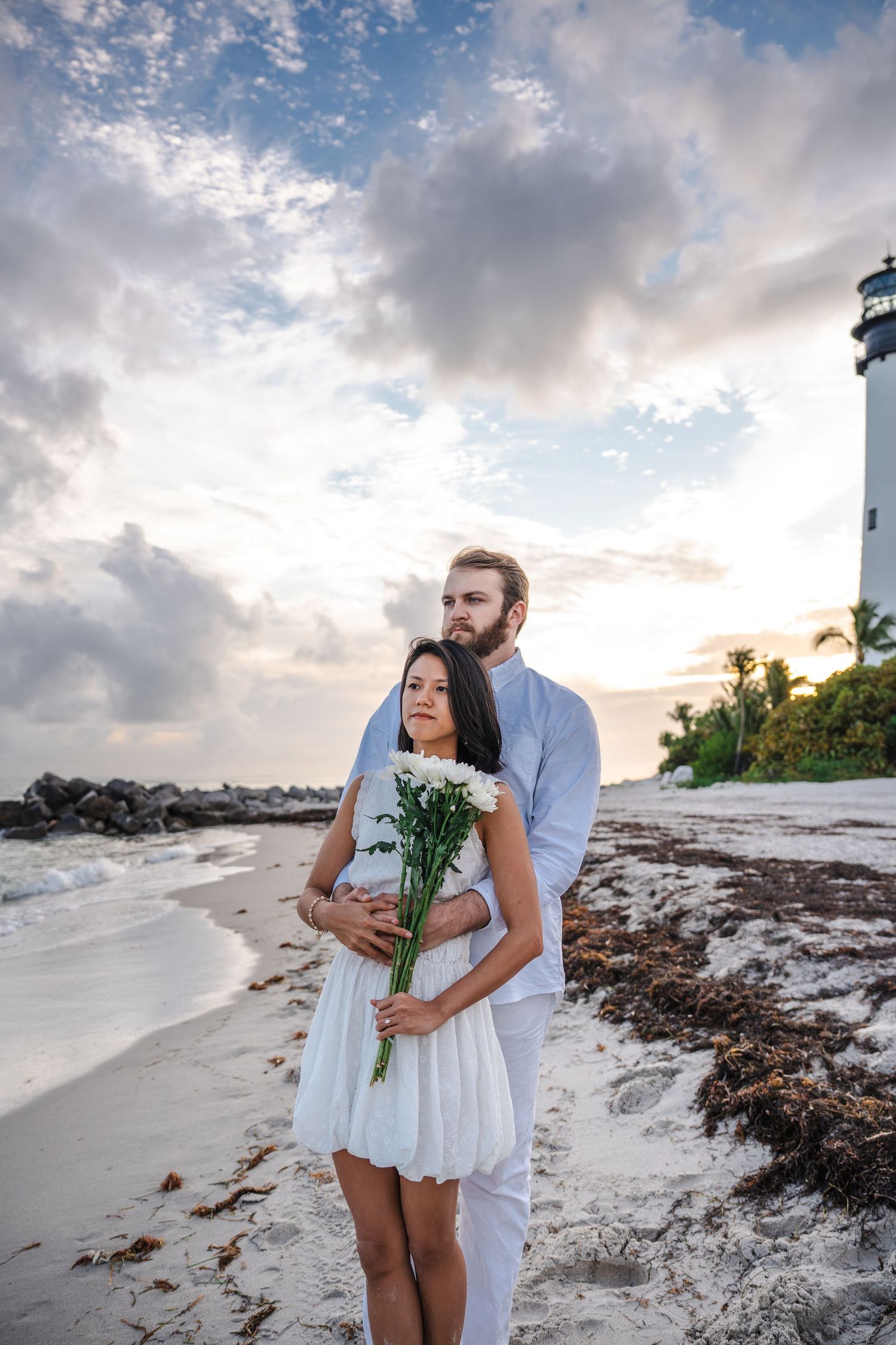 Engaged couple embracing on the shoreline at Bill Baggs Cape Florida, soft sunset light and coastal Miami engagement photos.