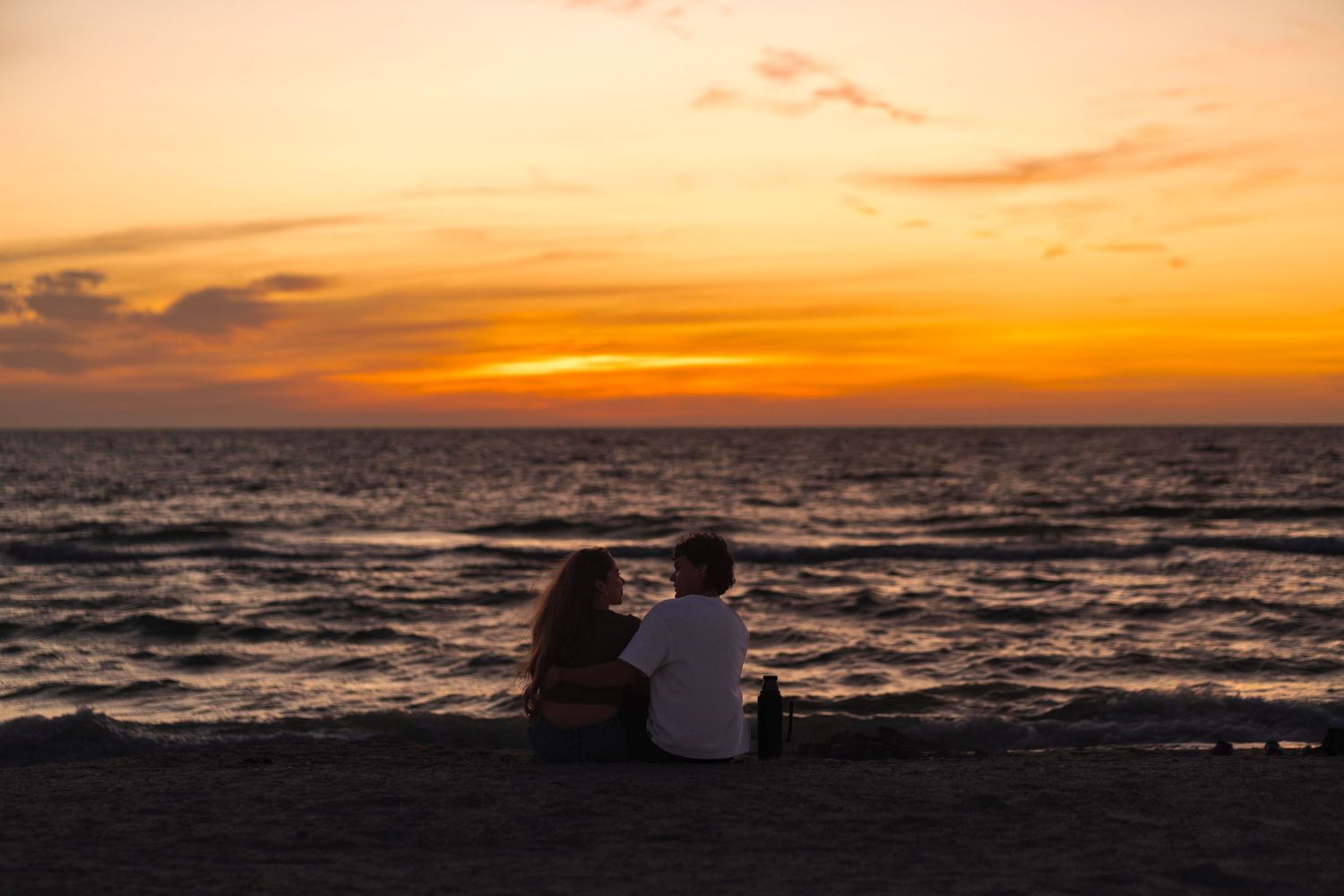 Beach sunset couples photo in South Florida by photographer, romantic silhouette sitting by the ocean at golden hour