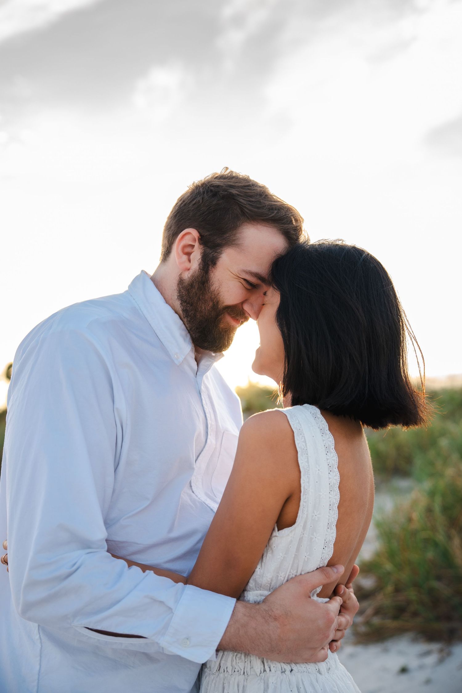 Close, intimate engagement portrait of a couple embracing at Bill Baggs Cape Florida with soft evening light.