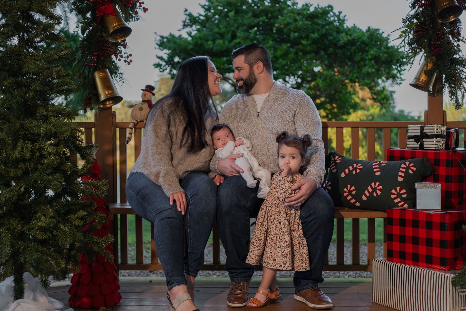 Festive family holiday mini session in Hollywood, FL – parents sharing a loving moment while their kids enjoy the Christmas setup.